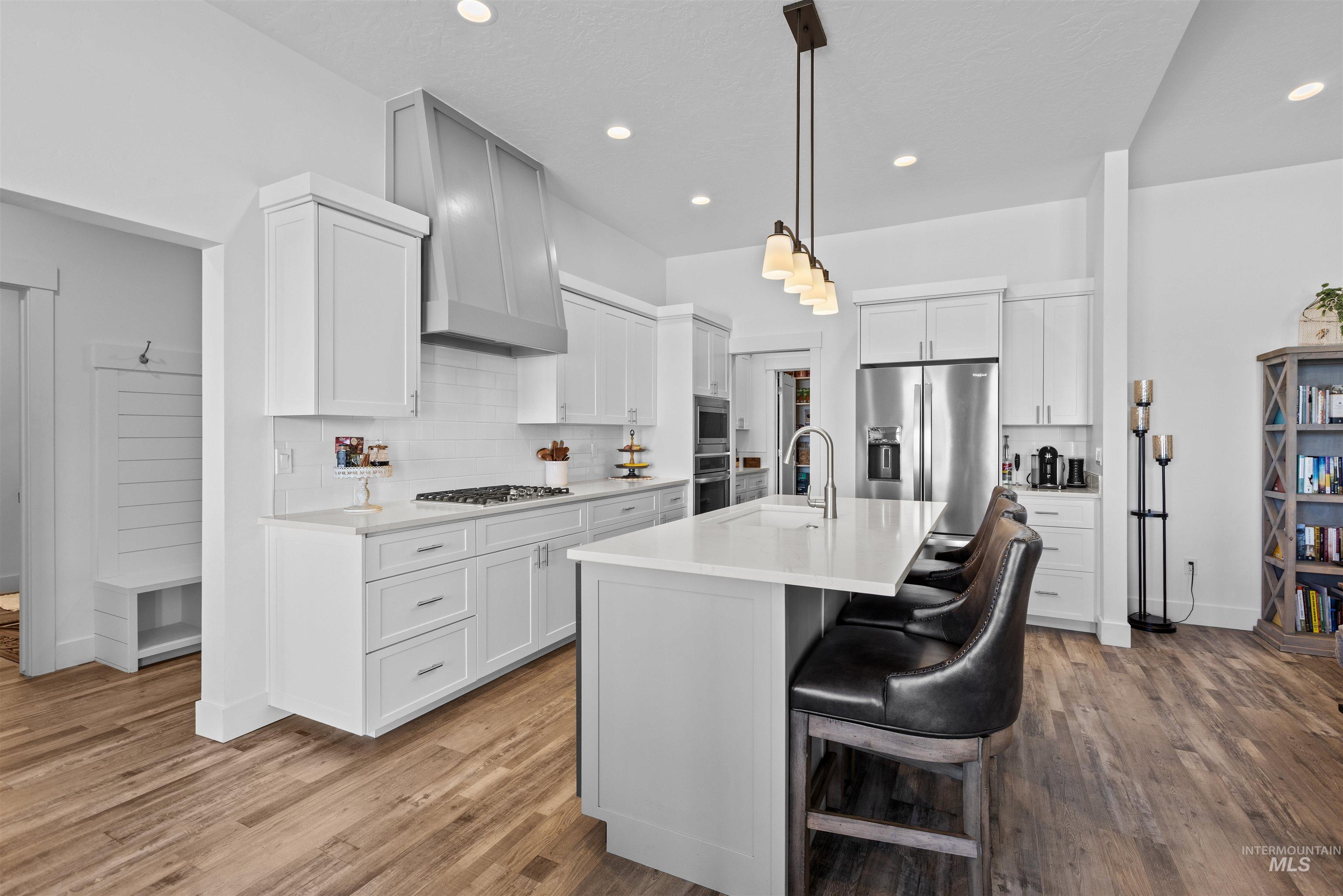 Kitchen featuring tasteful backsplash, a kitchen bar, a kitchen island with sink, light wood-style flooring, and recessed lighting