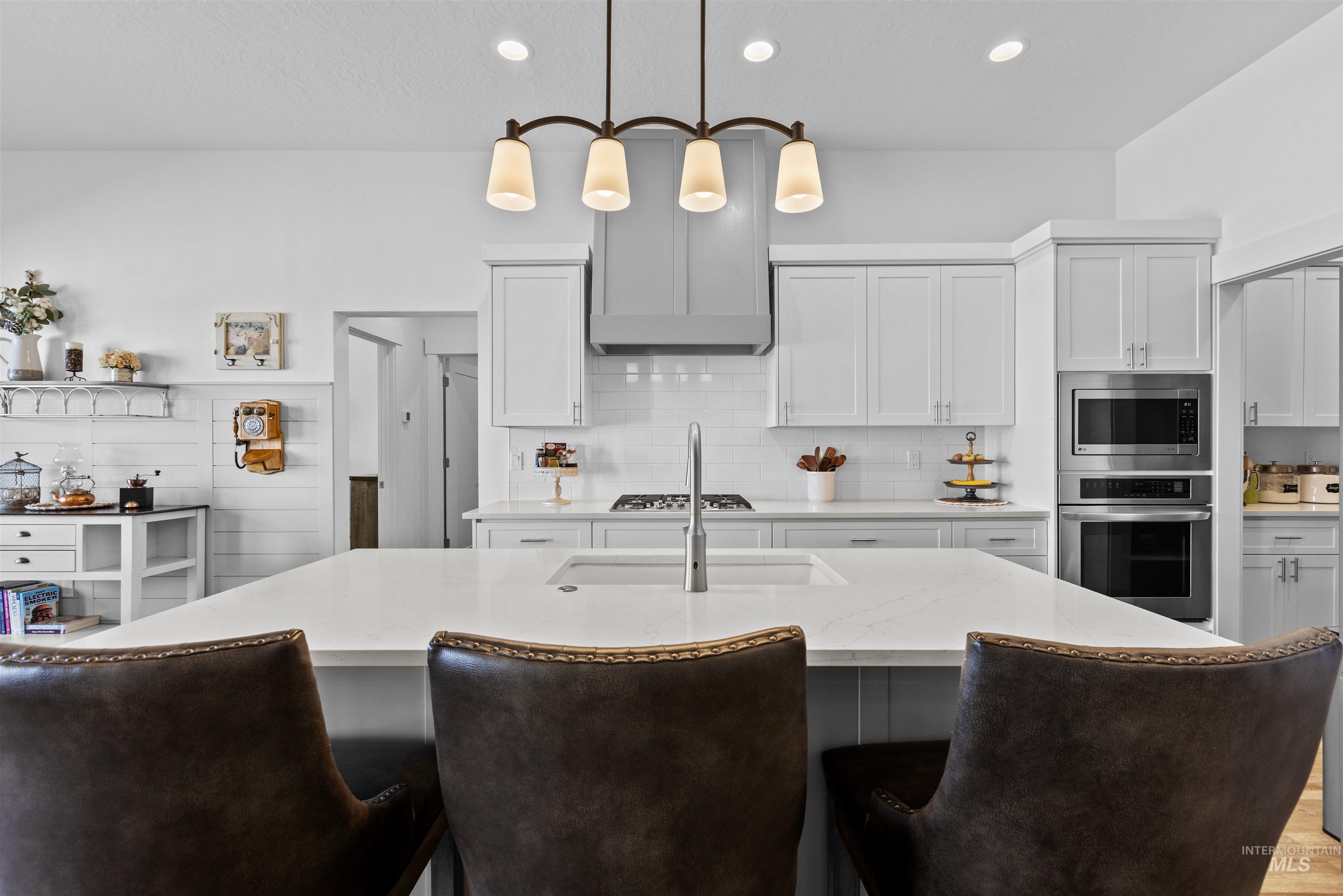 Kitchen featuring pendant lighting, white cabinetry, appliances with stainless steel finishes, decorative backsplash, and recessed lighting