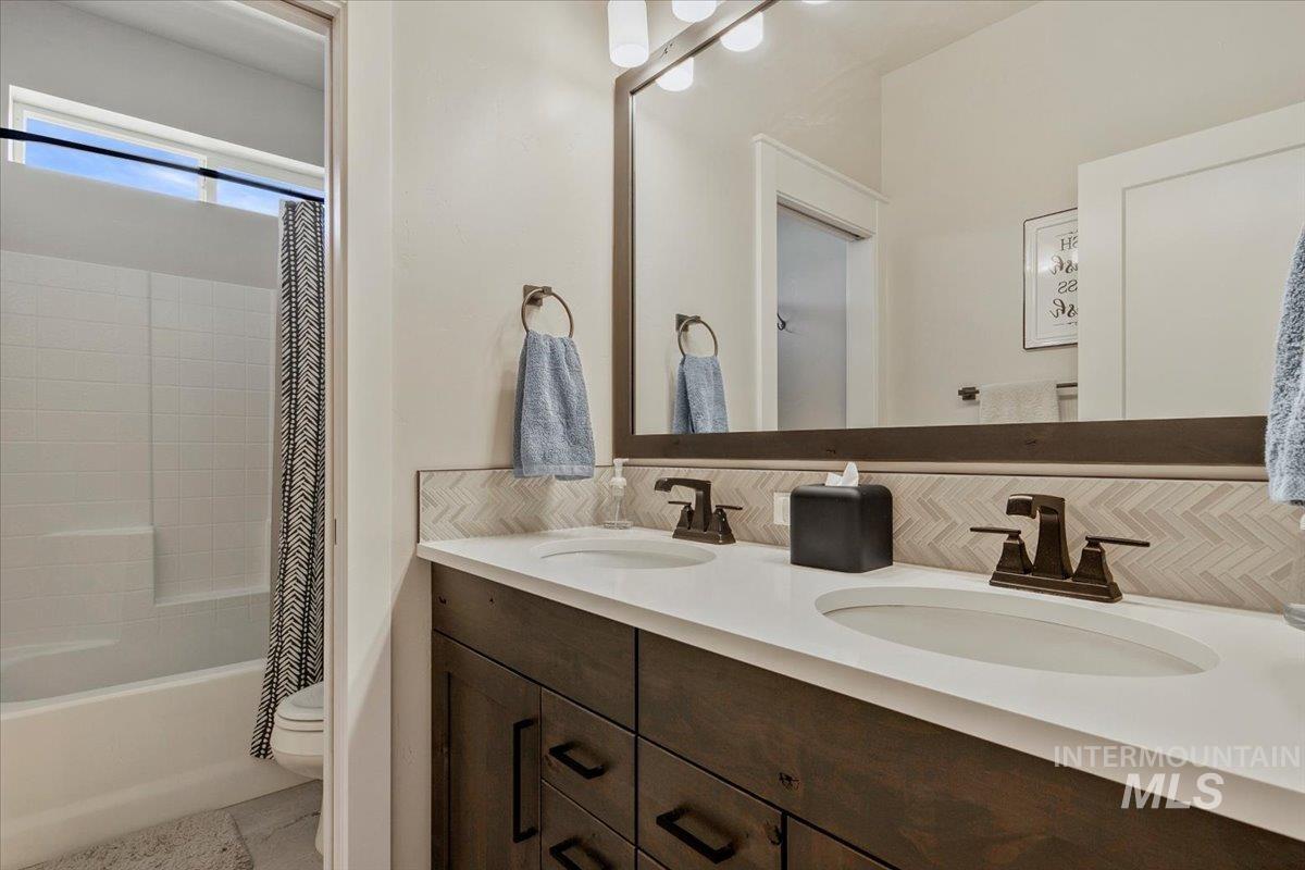 Bathroom featuring tasteful backsplash, double vanity, and shower / bath combo