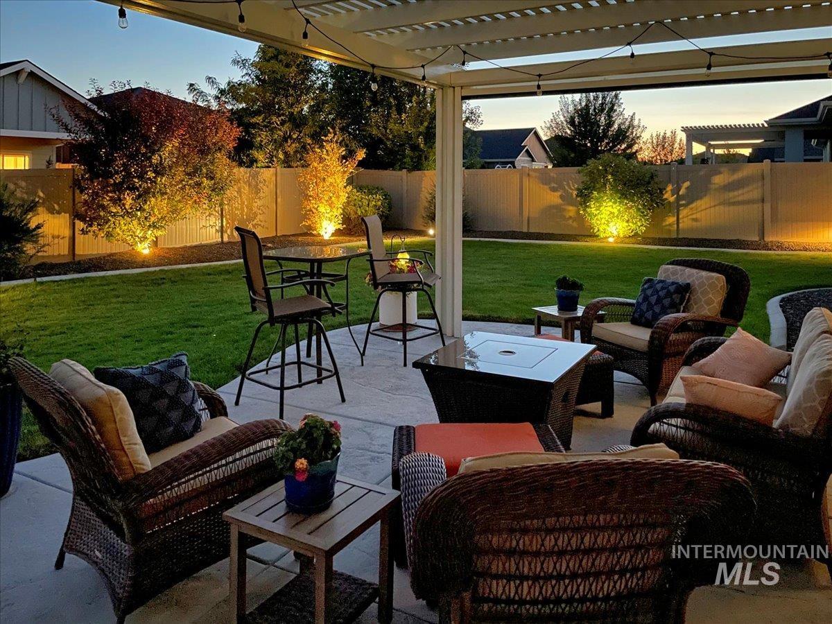 Patio terrace at dusk featuring an outdoor hangout area, a pergola, a patio, and a fenced backyard