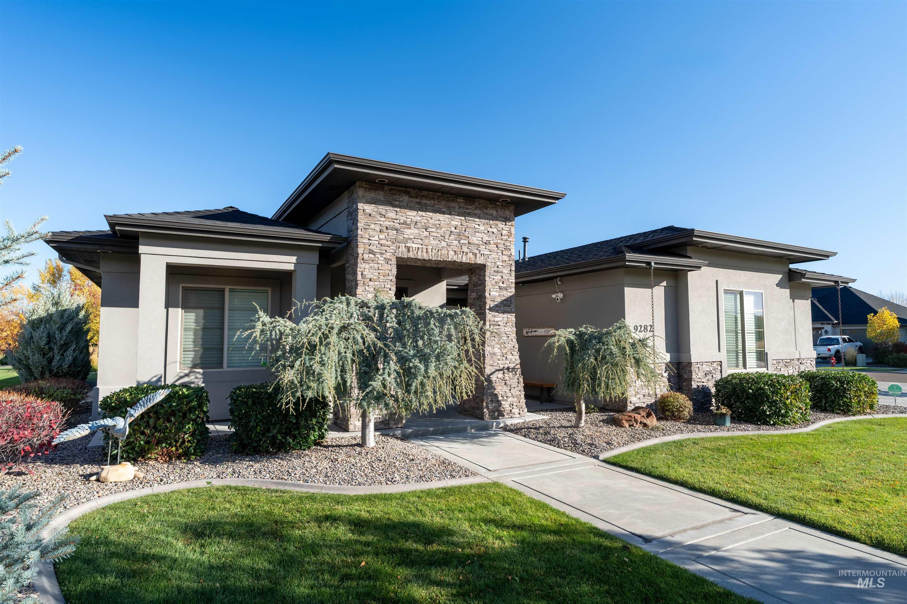 Prairie-style house with stone siding, a front yard, and stucco siding