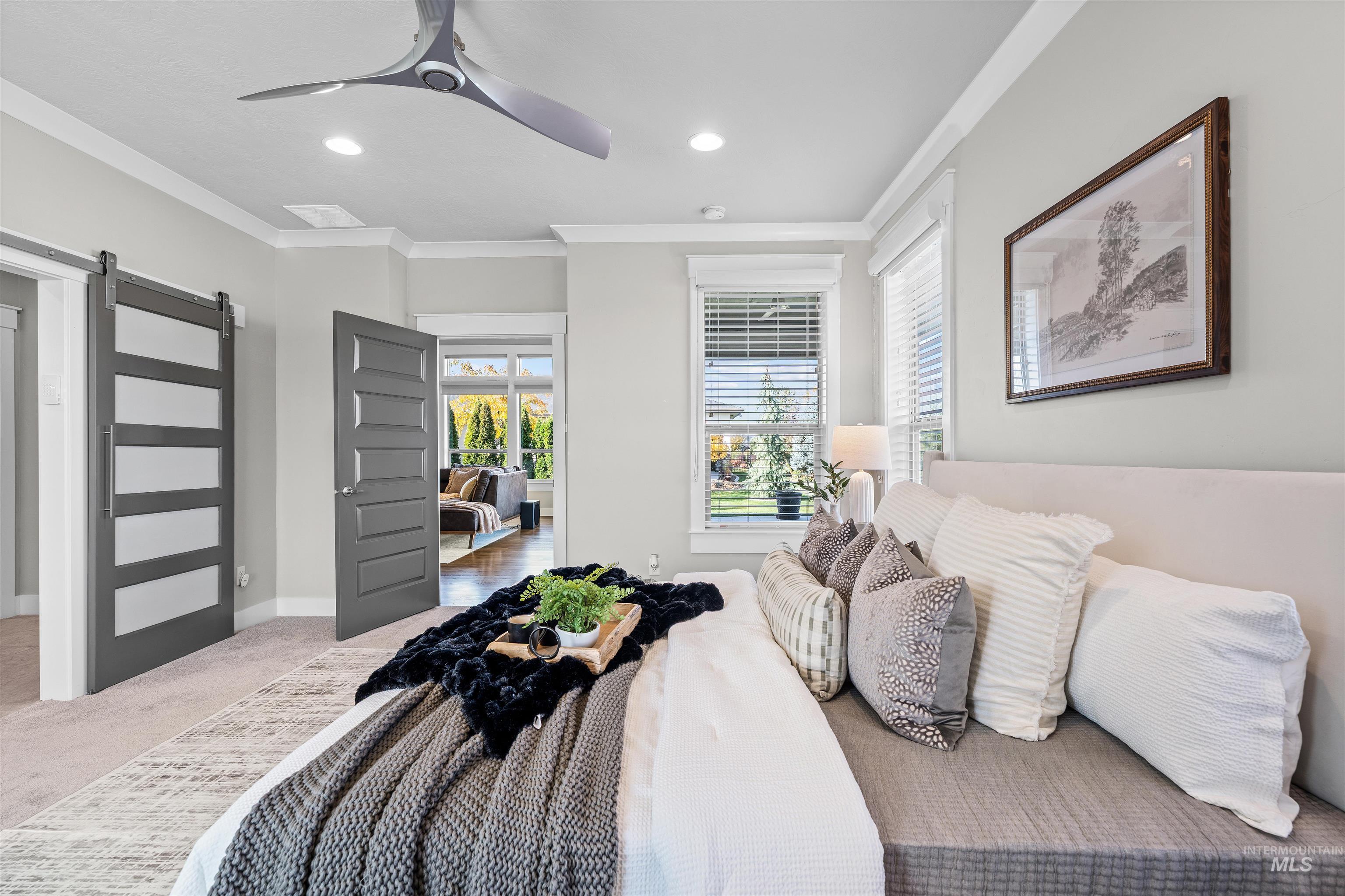 Carpeted bedroom featuring a barn door, crown molding, a ceiling fan, and recessed lighting