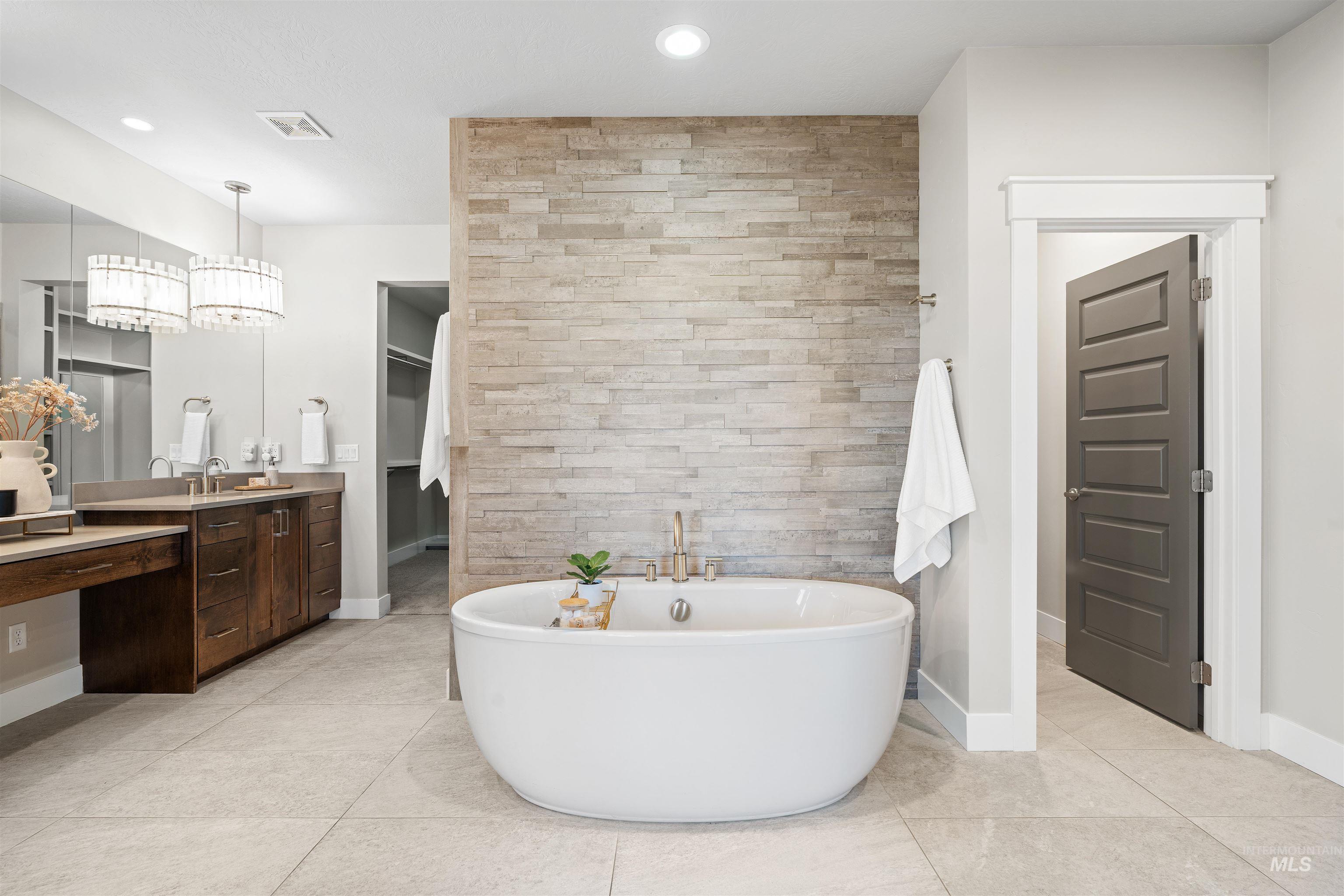 Full bath featuring vanity, a freestanding bath, light tile patterned floors, a spacious closet, and recessed lighting