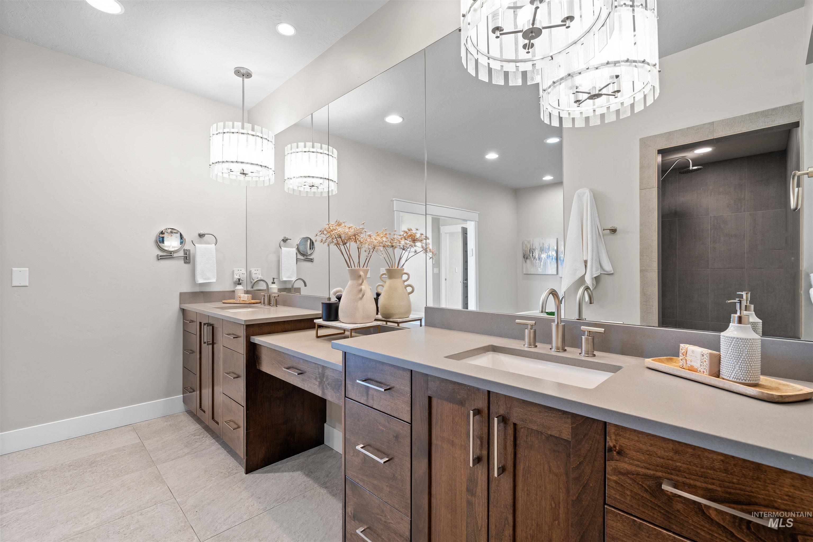 Full bathroom with double vanity, light tile patterned floors, a chandelier, a tile shower, and recessed lighting