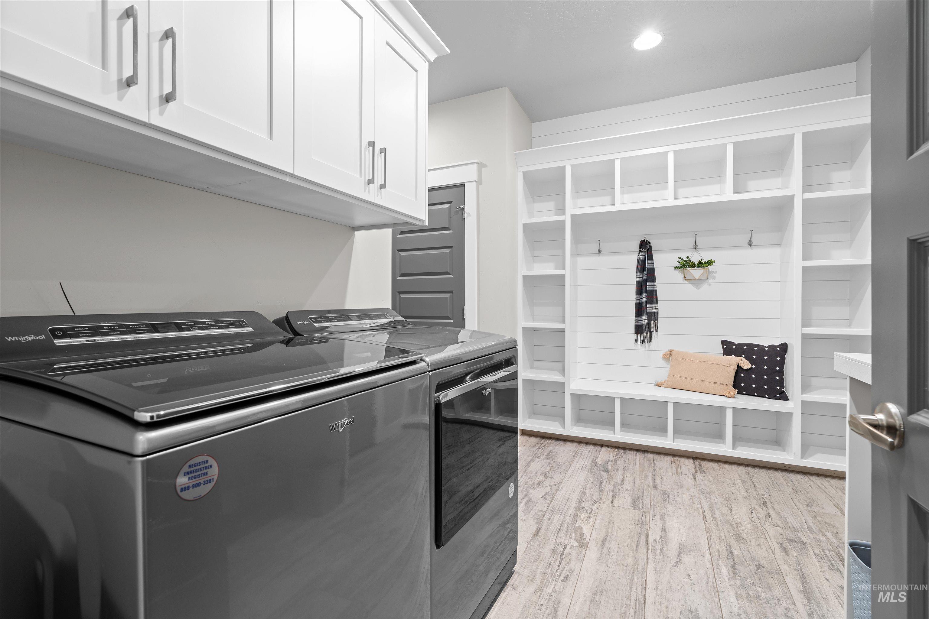 Washroom featuring light wood-style floors, cabinet space, washer and dryer, and recessed lighting