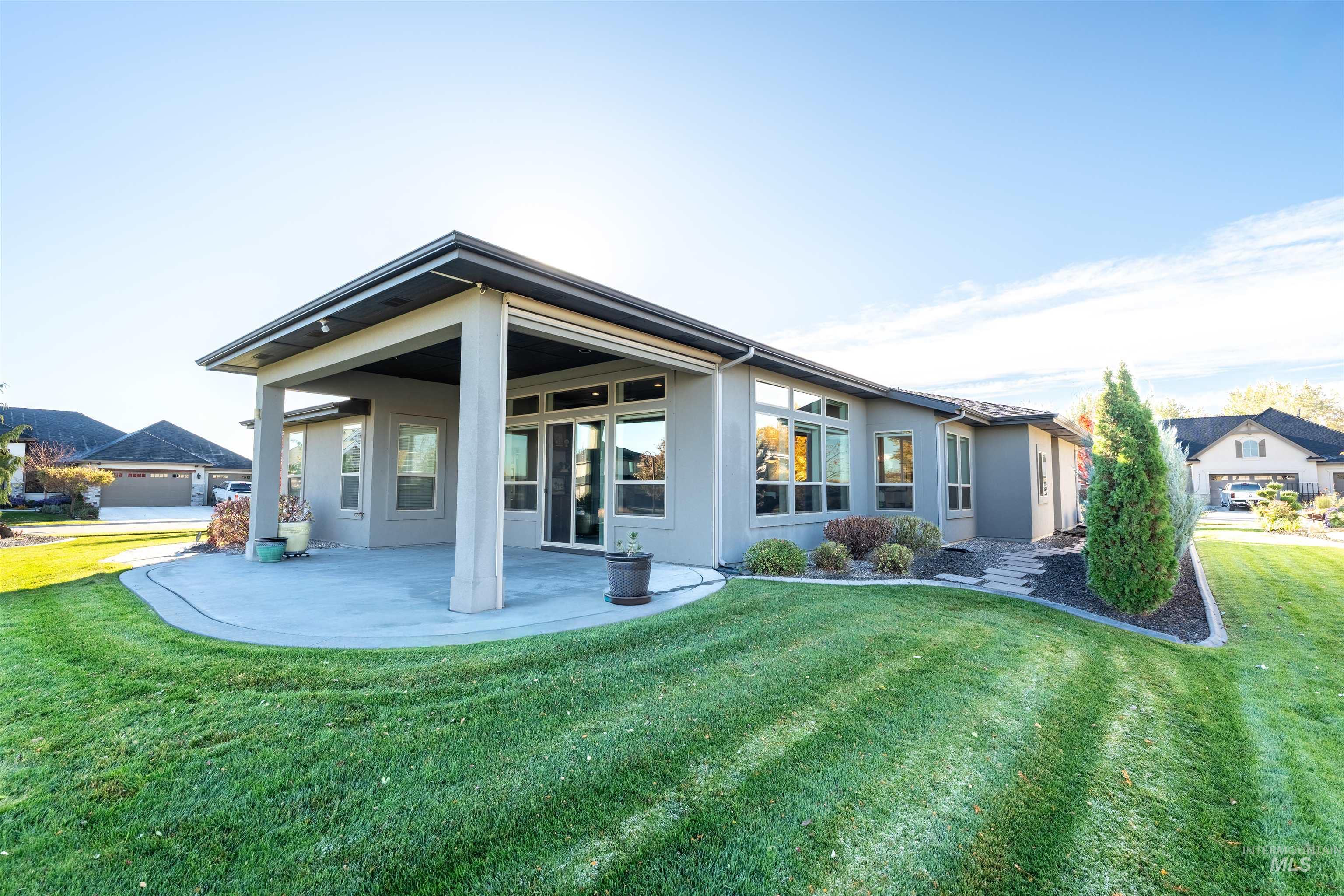 Rear view of property featuring a yard, a patio, and stucco siding