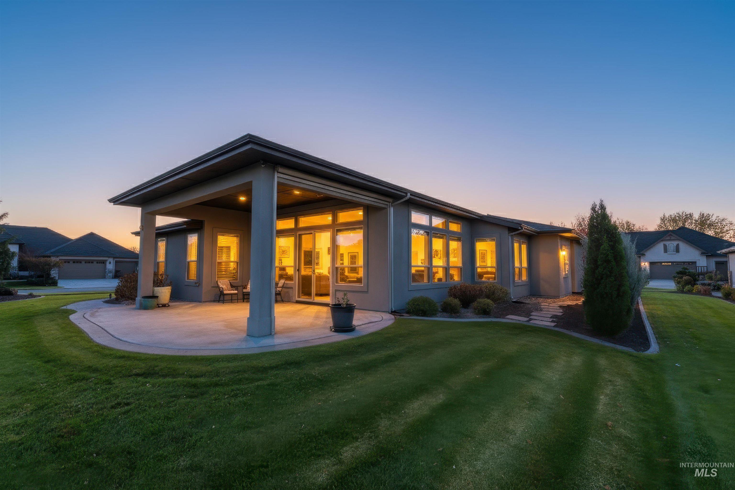 Rear view of property featuring a lawn, a patio, and stucco siding