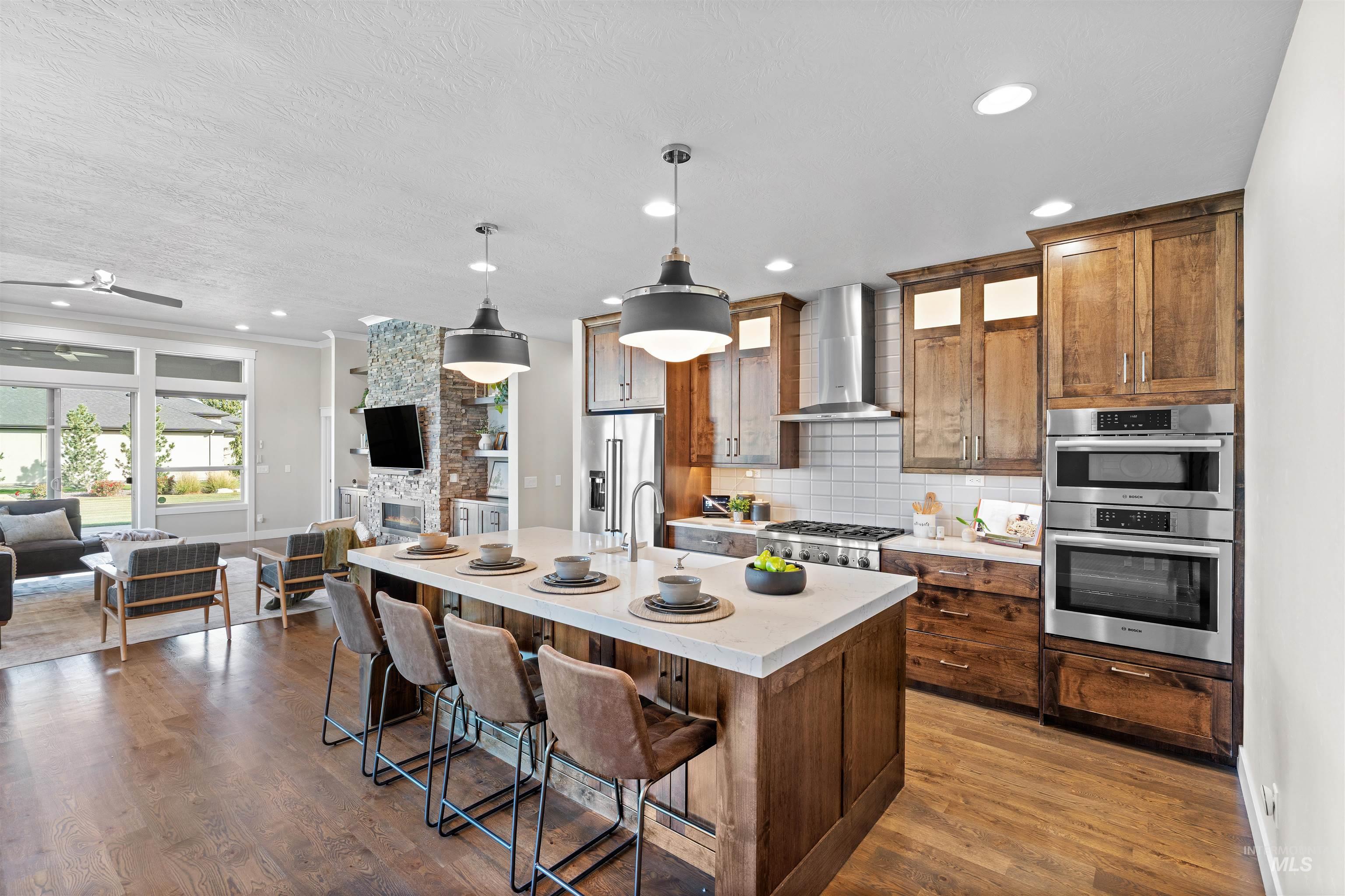 Kitchen featuring open floor plan, a breakfast bar area, decorative light fixtures, a center island with sink, and tasteful backsplash