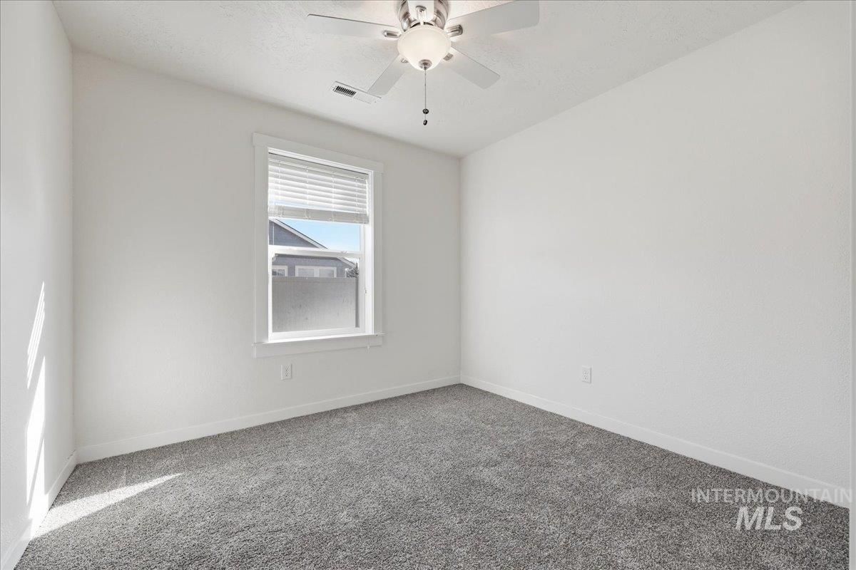 Carpeted empty room with baseboards and ceiling fan