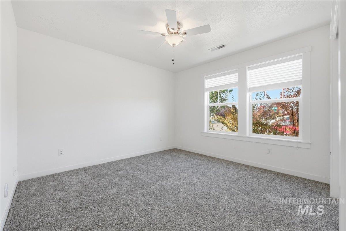 Unfurnished room featuring carpet, a ceiling fan, and a textured ceiling