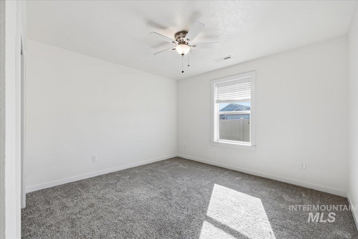 Carpeted spare room with baseboards and a ceiling fan
