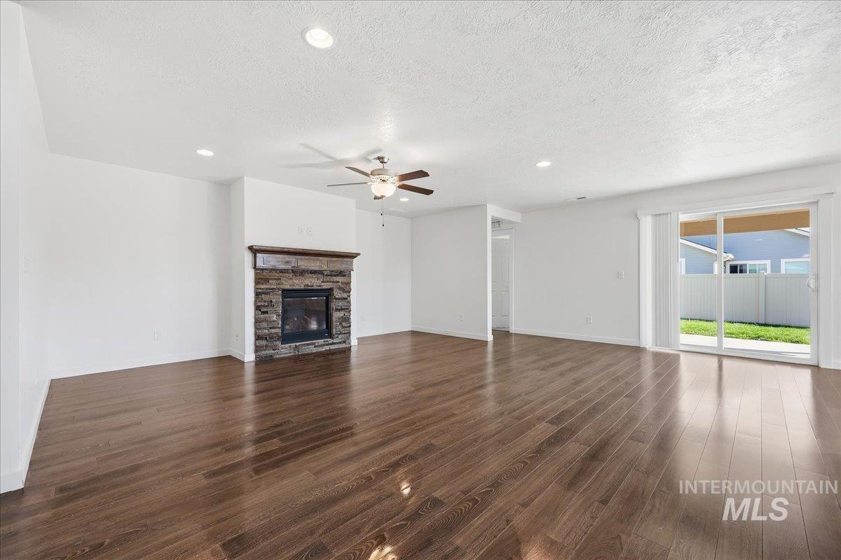 Unfurnished living room with dark wood finished floors, recessed lighting, a textured ceiling, a ceiling fan, and a fireplace