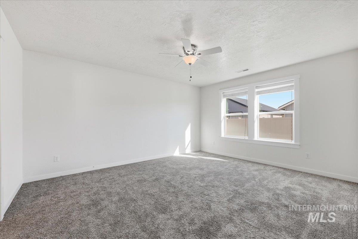 Spare room with carpet, a ceiling fan, and a textured ceiling