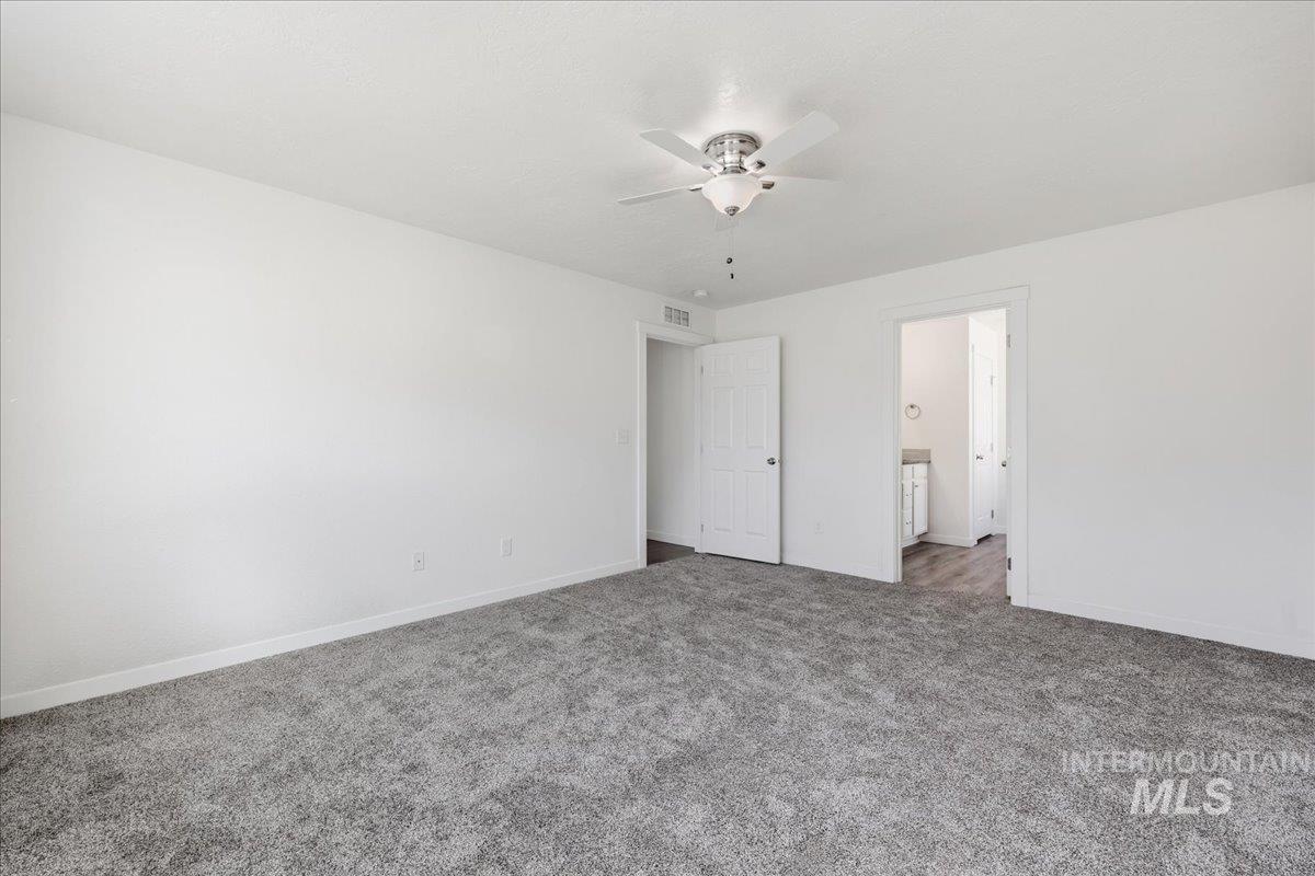 Unfurnished bedroom featuring carpet floors, ceiling fan, and connected bathroom