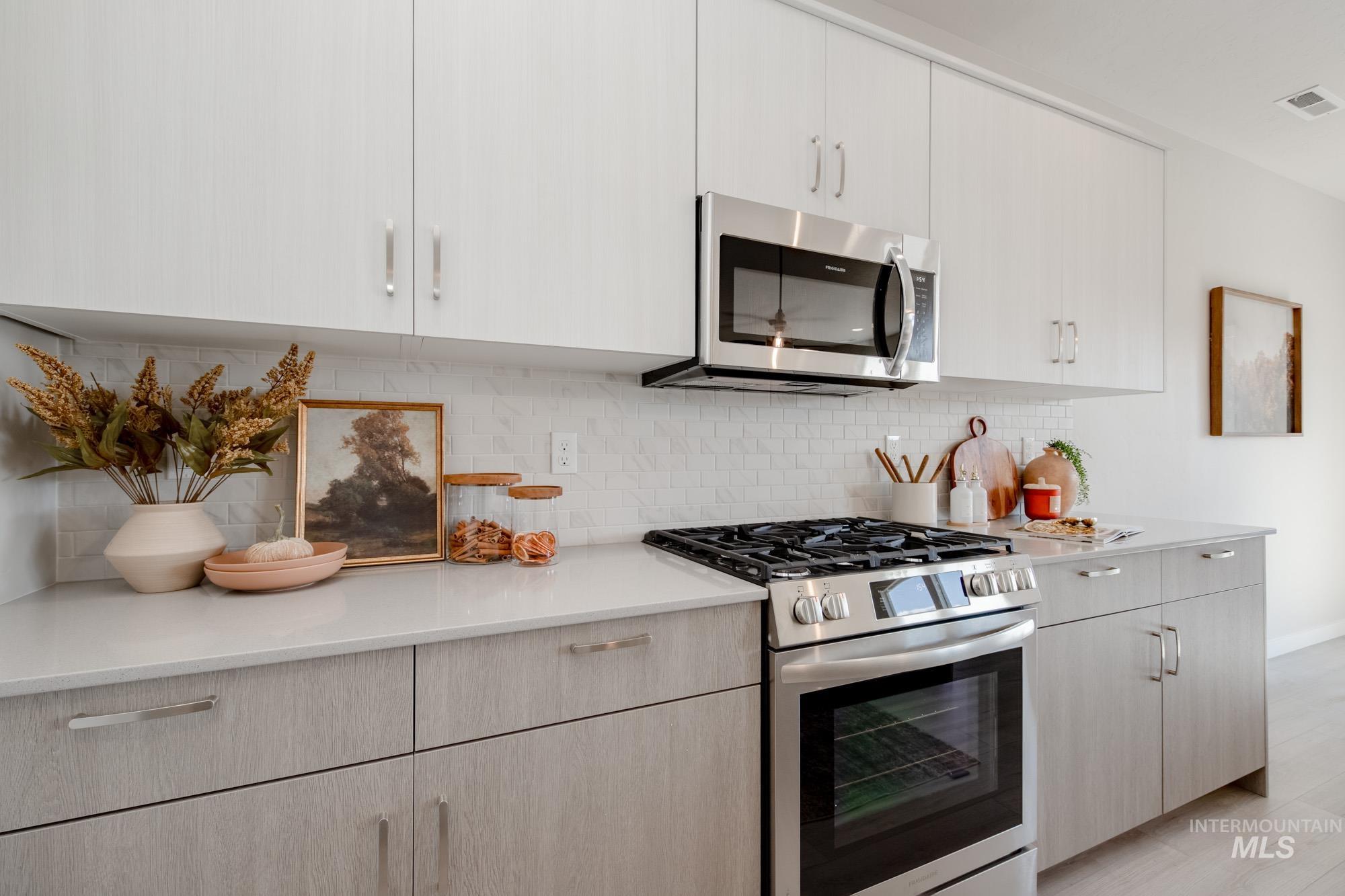 Kitchen featuring appliances with stainless steel finishes, decorative backsplash, modern cabinets, and light stone counters