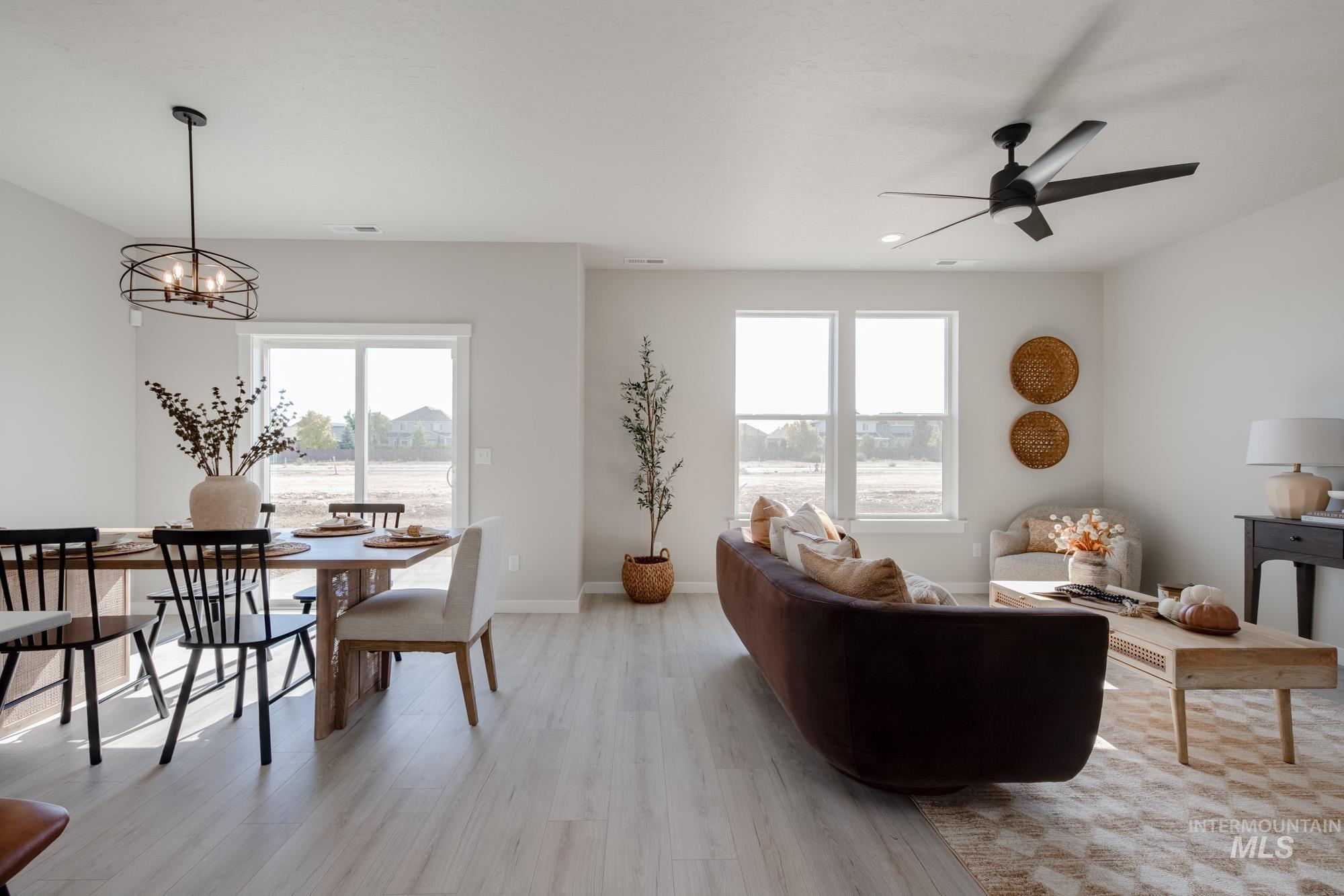 Living area with light wood-style floors, a chandelier, and a ceiling fan