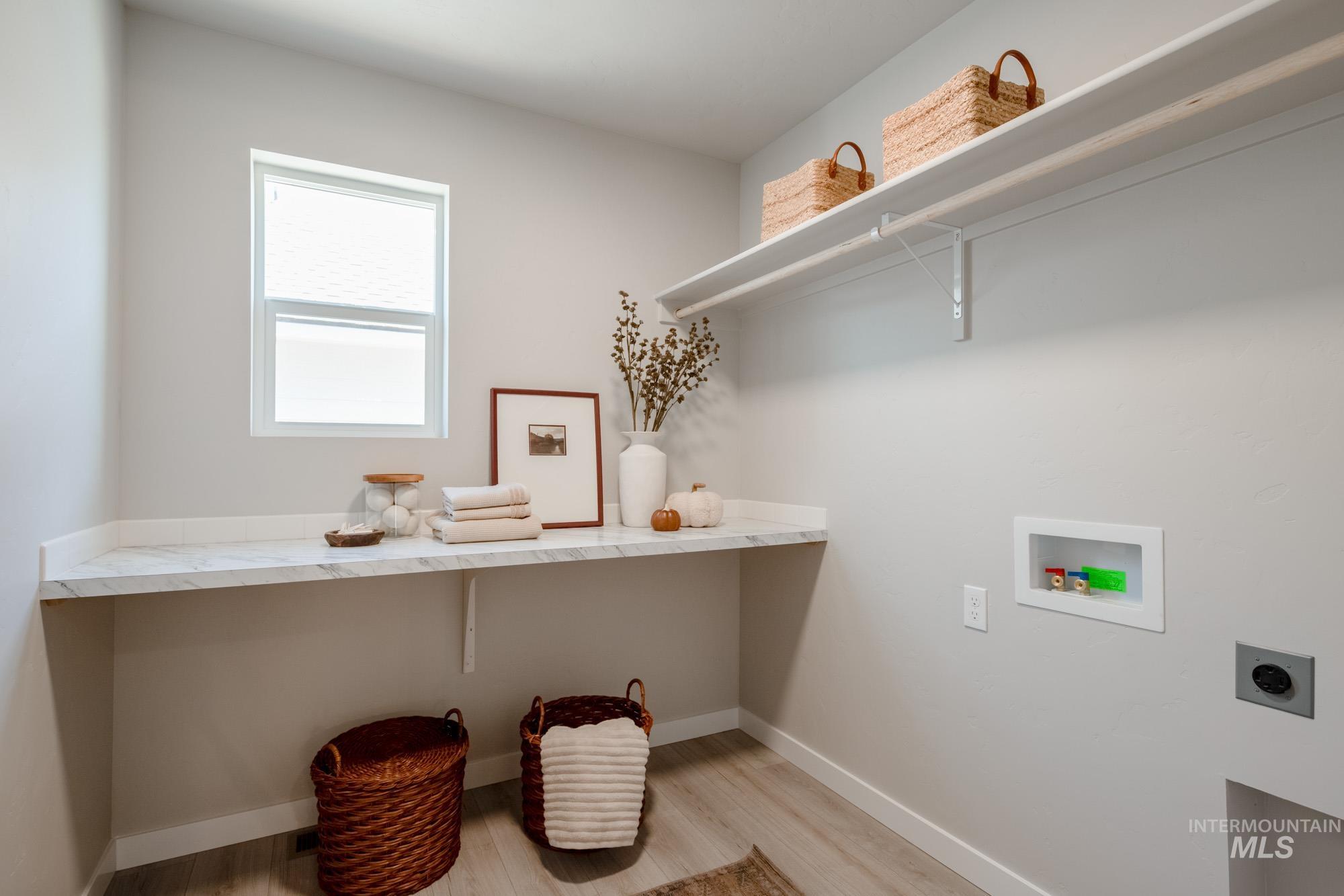 Laundry area with light wood-type flooring, hookup for an electric dryer, and washer hookup