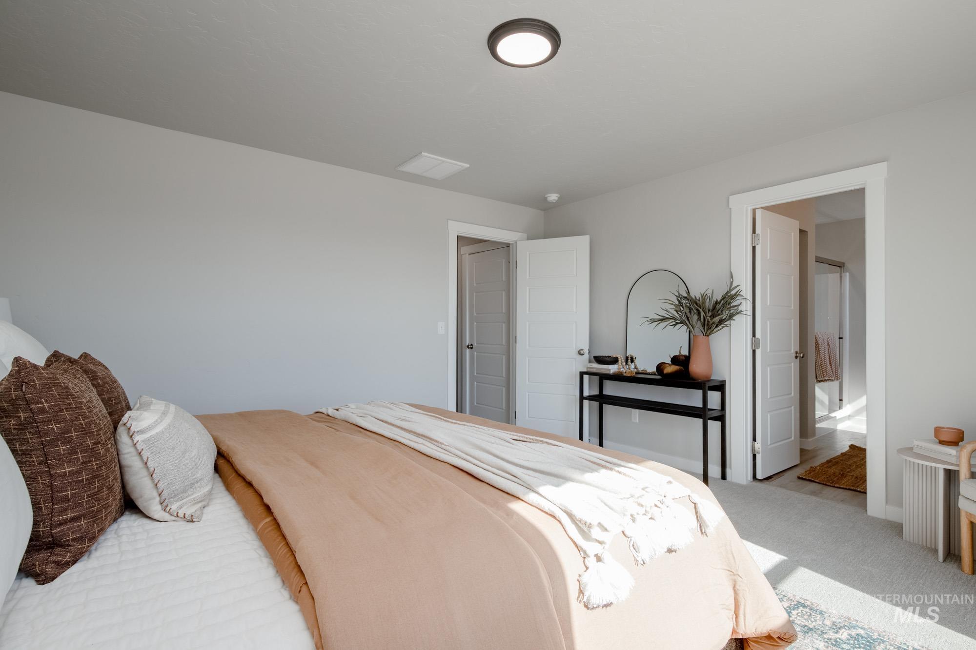 Carpeted bedroom with ensuite bath and baseboards