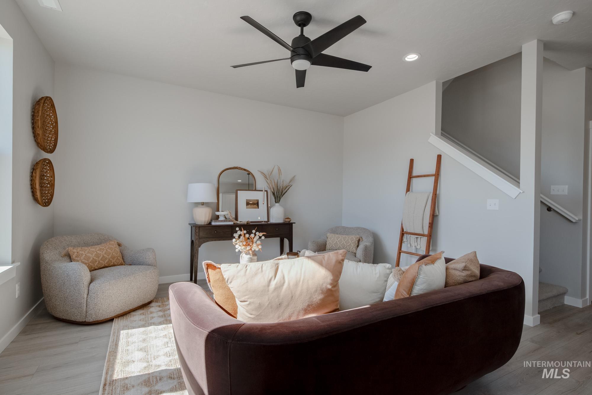 Living area featuring light wood-type flooring, a ceiling fan, recessed lighting, and stairs
