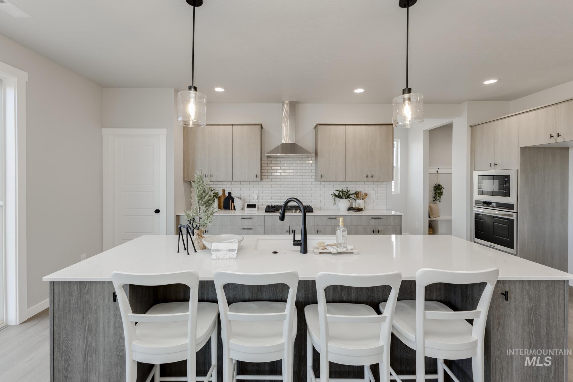 Kitchen with backsplash, a center island with sink, hanging light fixtures, a kitchen bar, and recessed lighting