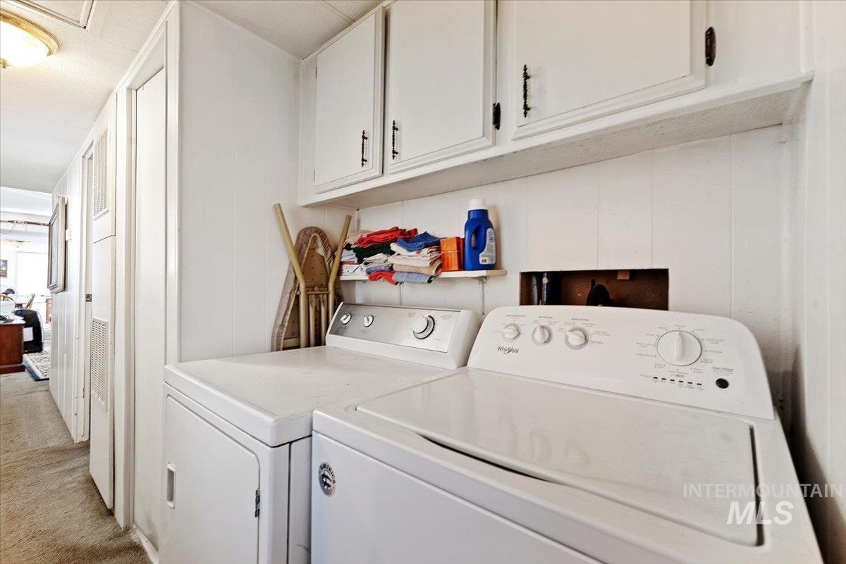 Laundry room featuring separate washer and dryer, cabinet space, and light colored carpet