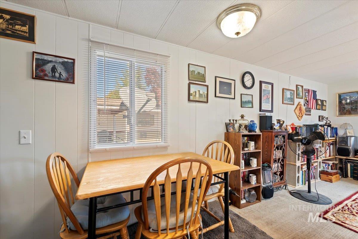 Carpeted dining room featuring a decorative wall