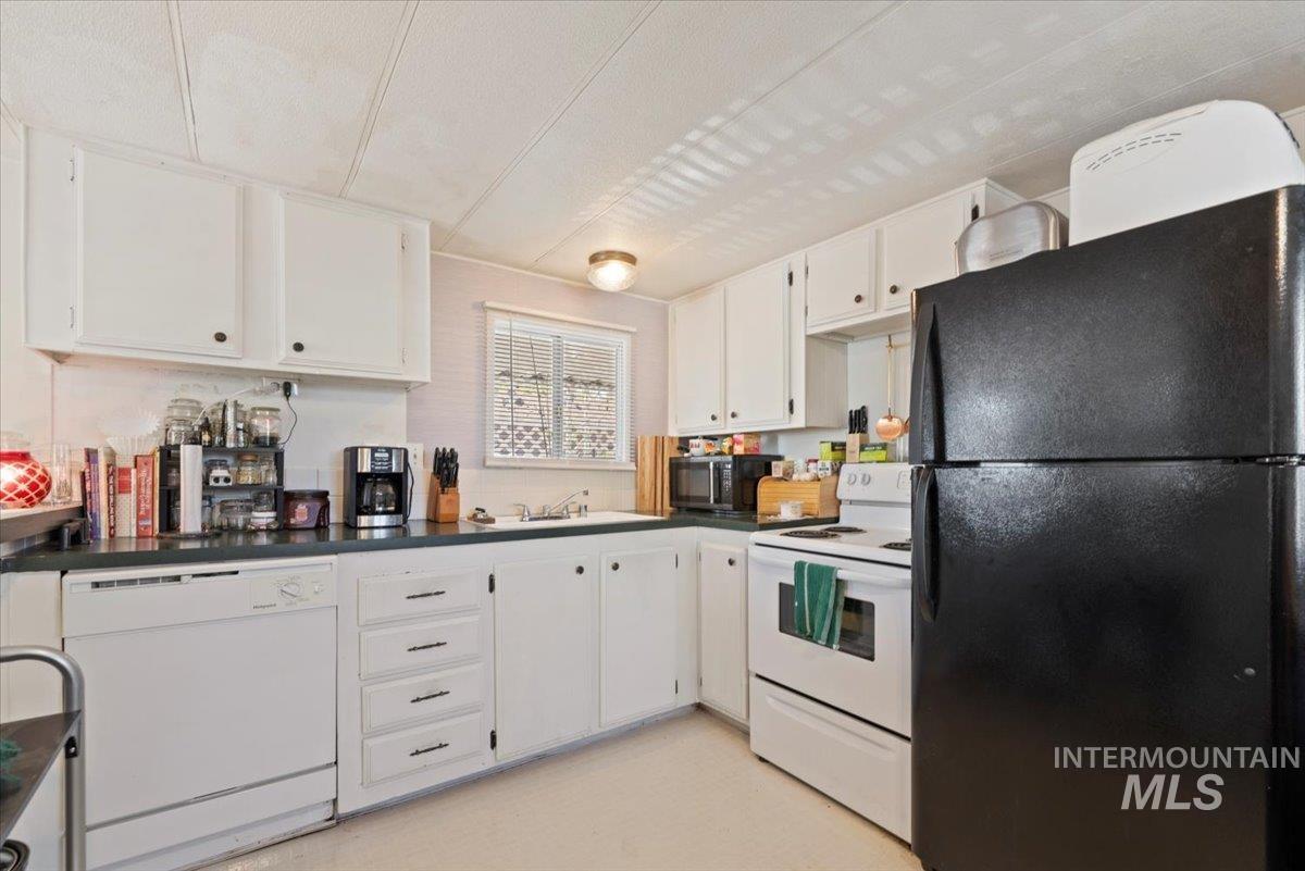 Kitchen with black appliances, dark countertops, and white cabinets