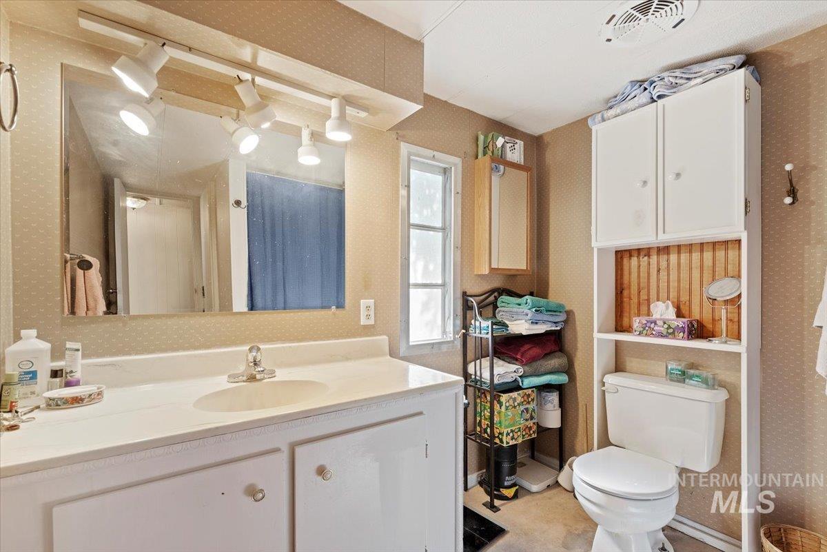 Bathroom with wallpapered walls and vanity