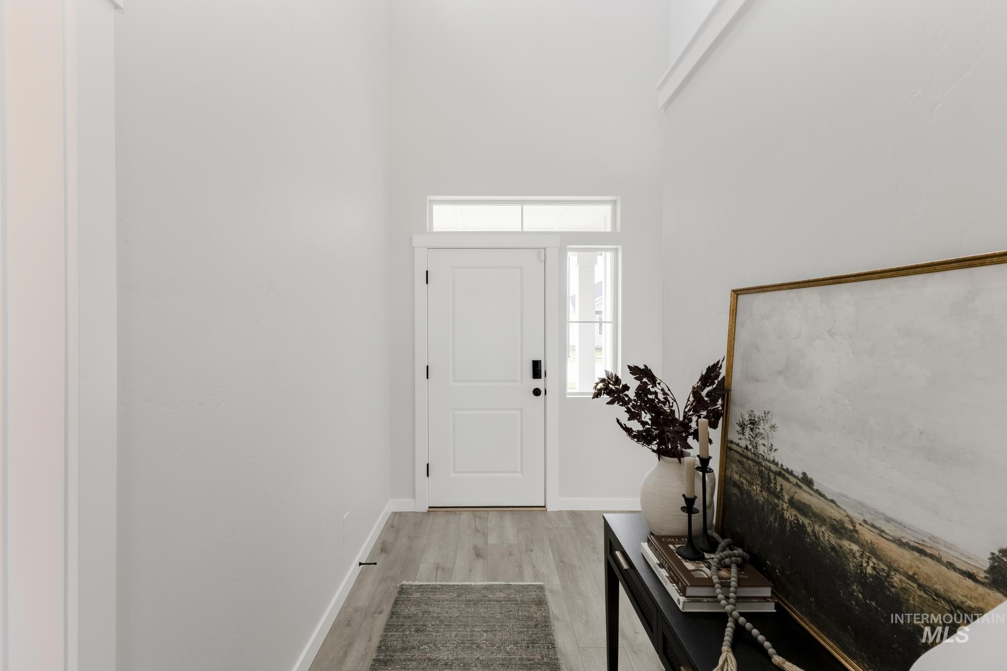 Entryway featuring light wood-style flooring and a towering ceiling