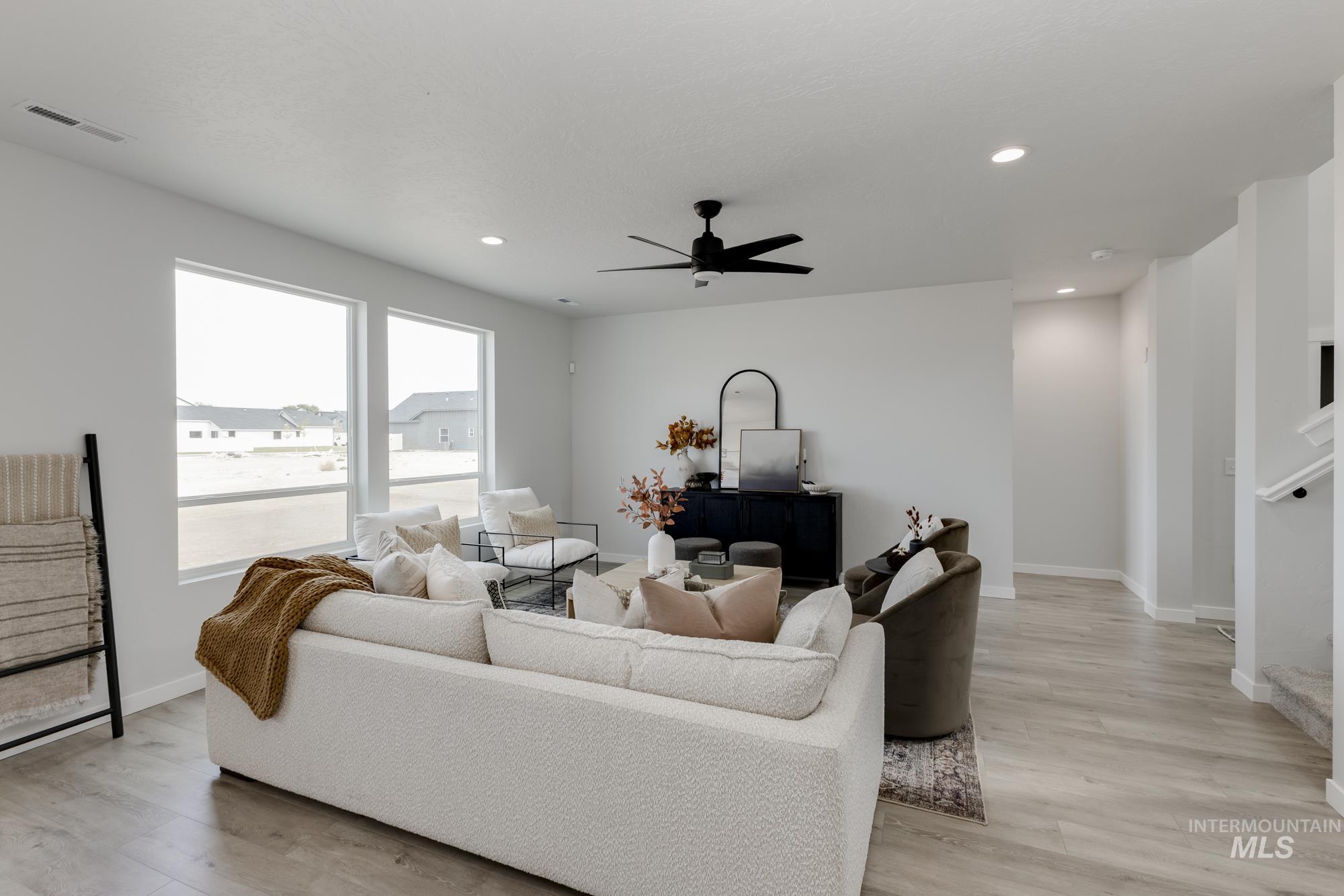 Living area featuring light wood-type flooring, recessed lighting, ceiling fan, and stairway