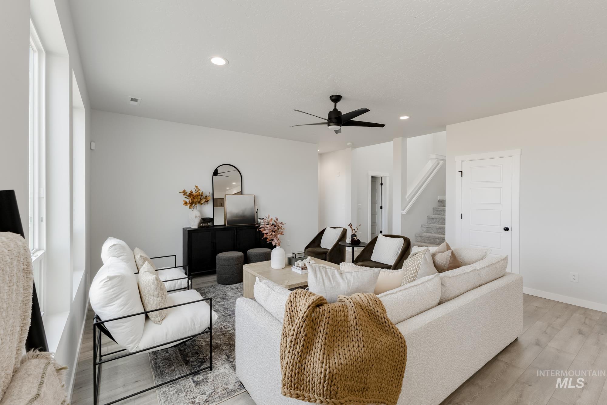 Living area featuring recessed lighting, ceiling fan, light wood-type flooring, and stairs