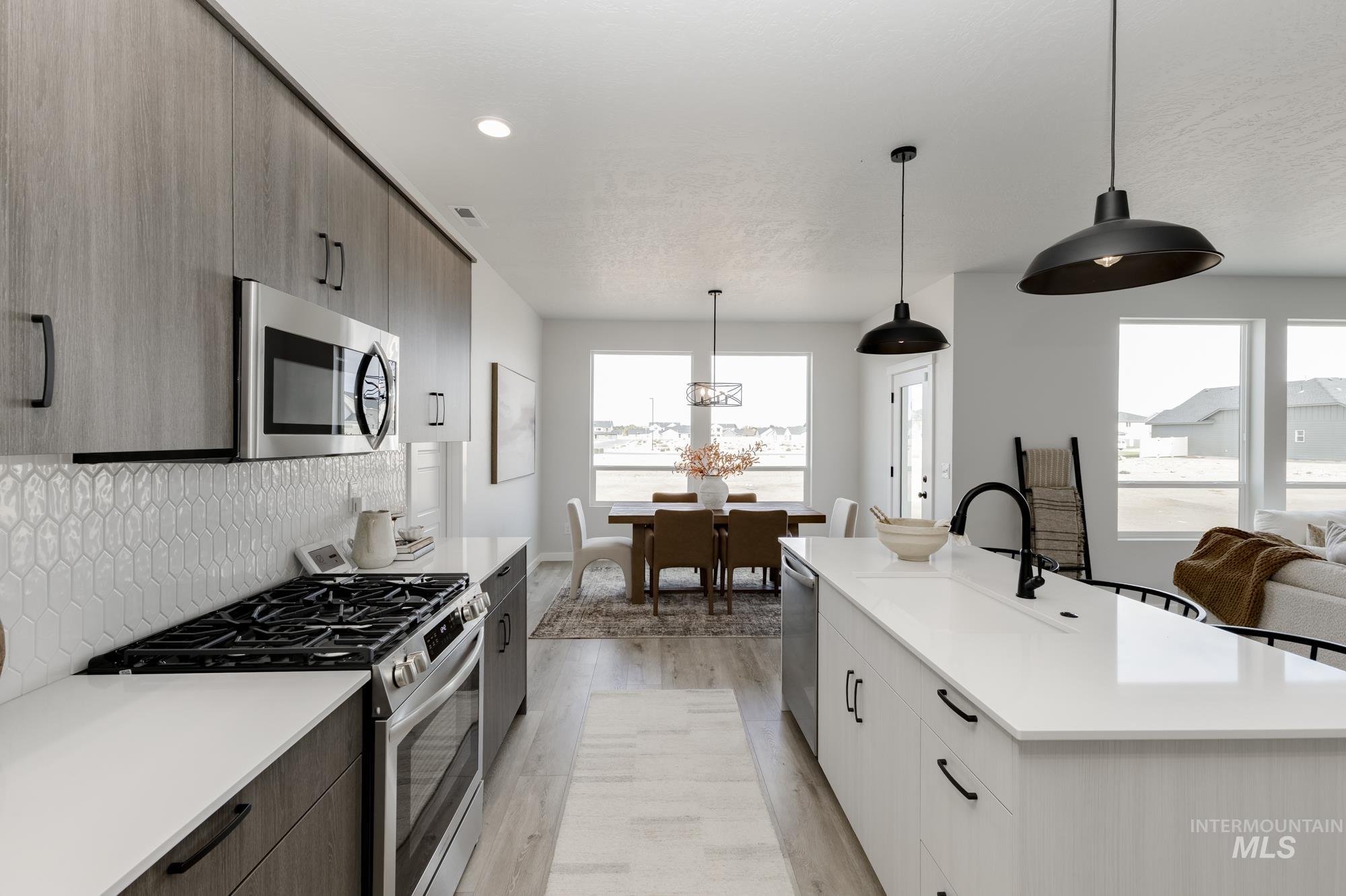 Kitchen featuring appliances with stainless steel finishes, modern cabinets, pendant lighting, light wood finished floors, and plenty of natural light