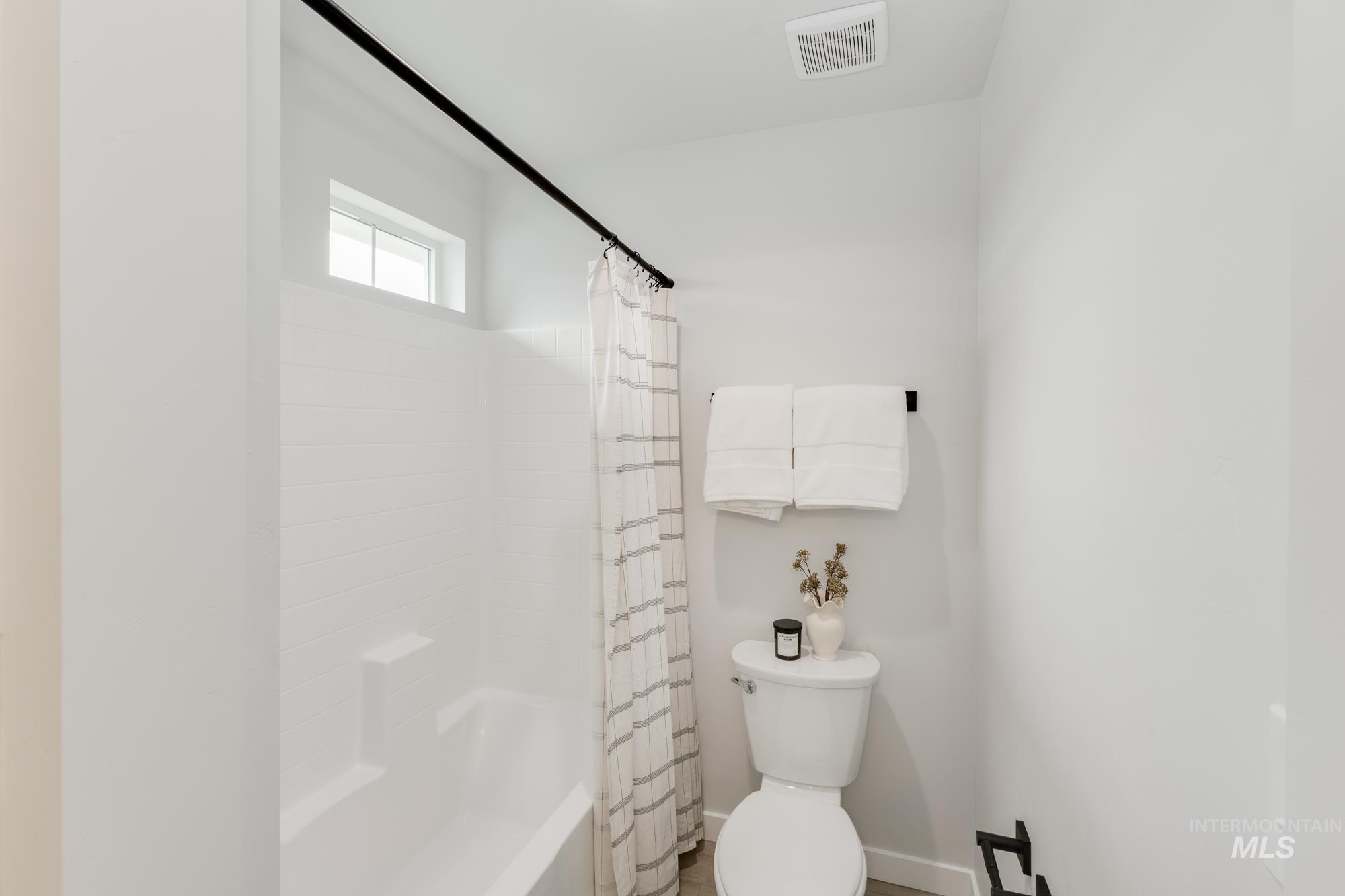 Full bathroom with toilet and shower / bath combo with shower curtain