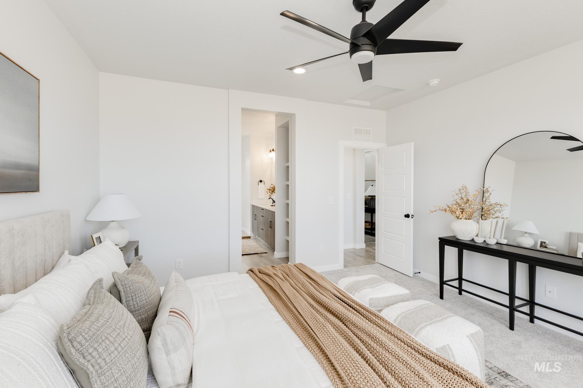 Bedroom with light colored carpet, ceiling fan, and ensuite bath