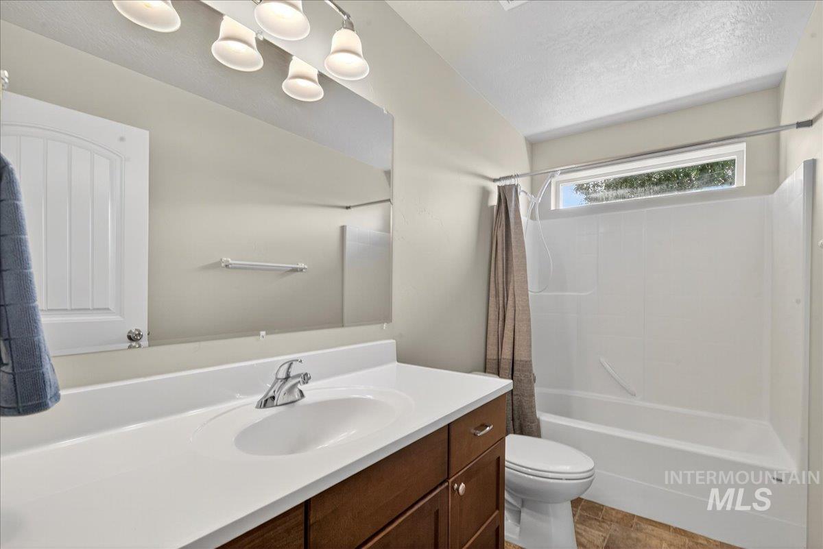 Full bath featuring vanity, shower / tub combo, and a textured ceiling