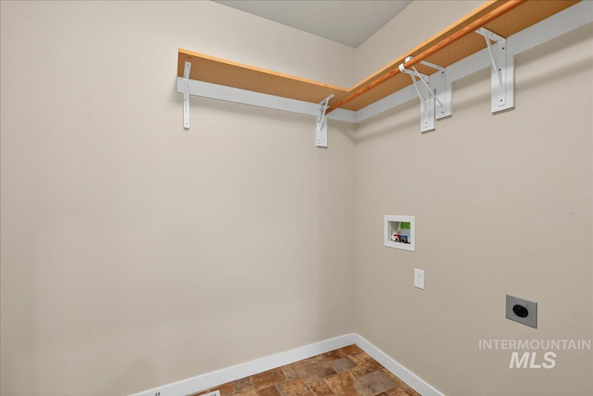 Laundry area with stone finish flooring, hookup for a washing machine, and electric dryer hookup
