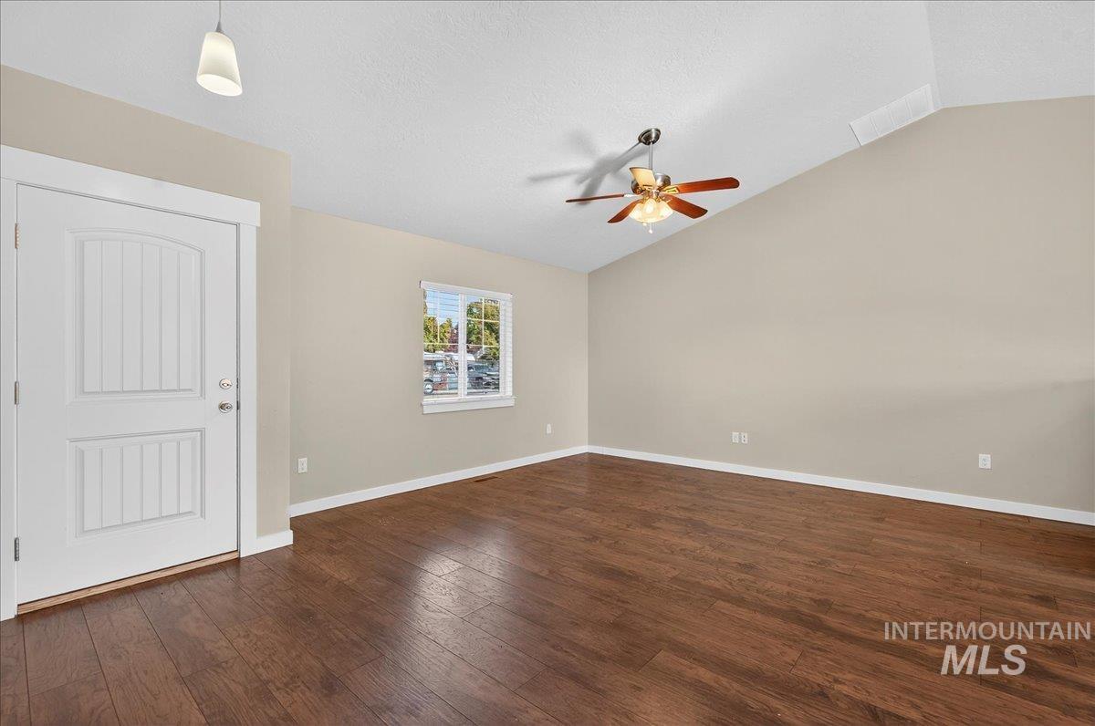 Spare room featuring lofted ceiling, dark wood-style floors, a textured ceiling, and a ceiling fan