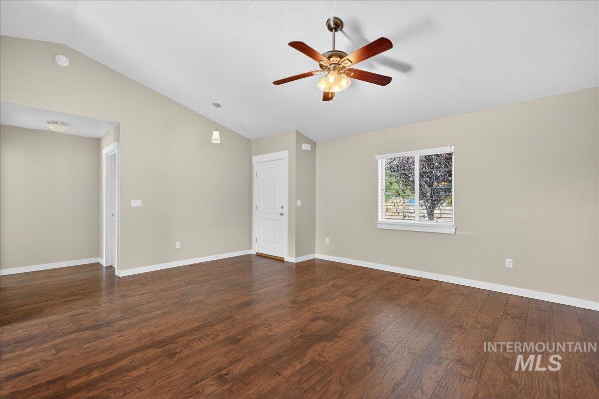 Spare room with lofted ceiling, dark wood-type flooring, a ceiling fan, and a textured ceiling