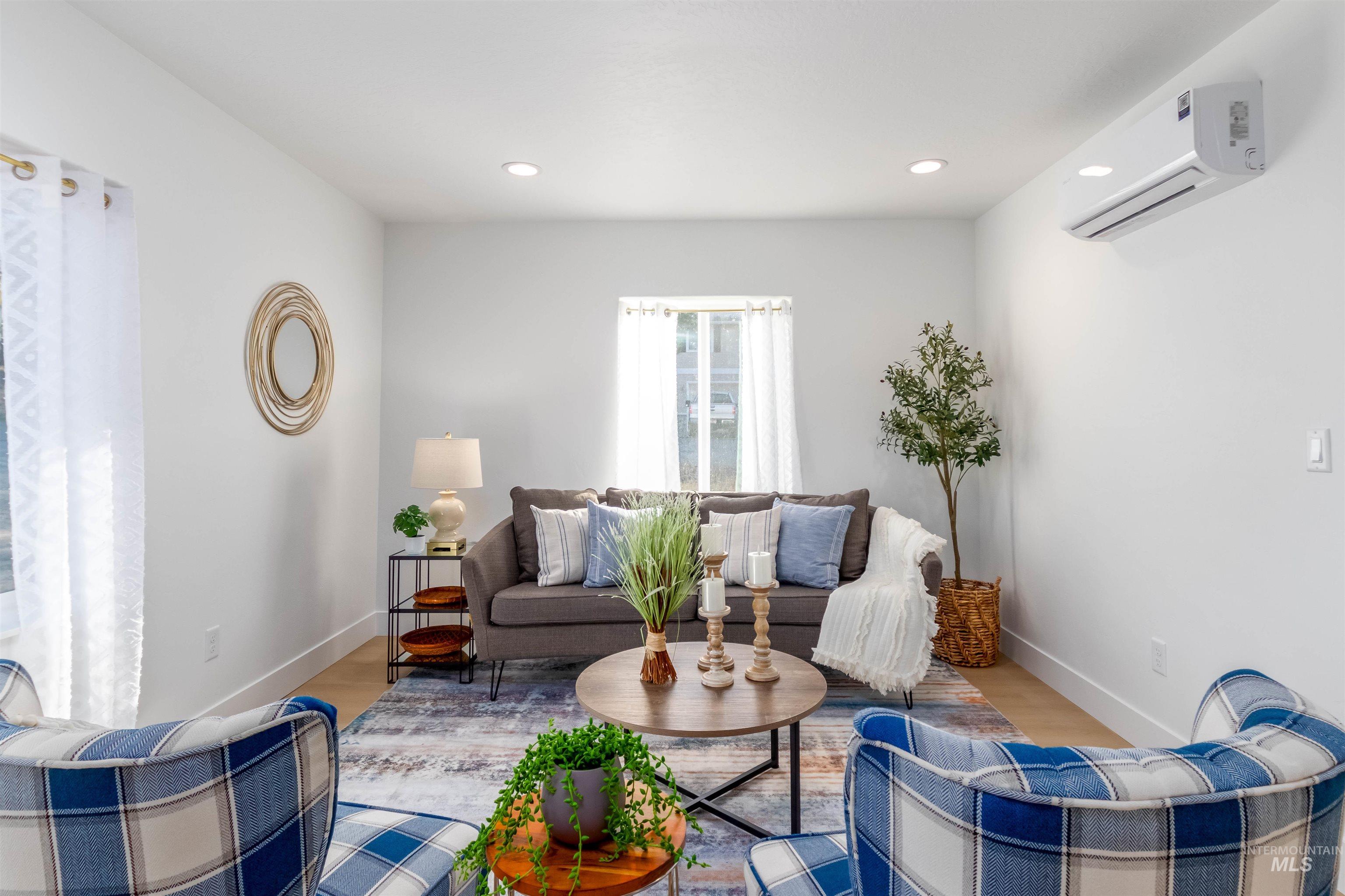 Living room with wood finished floors, an AC wall unit, and recessed lighting