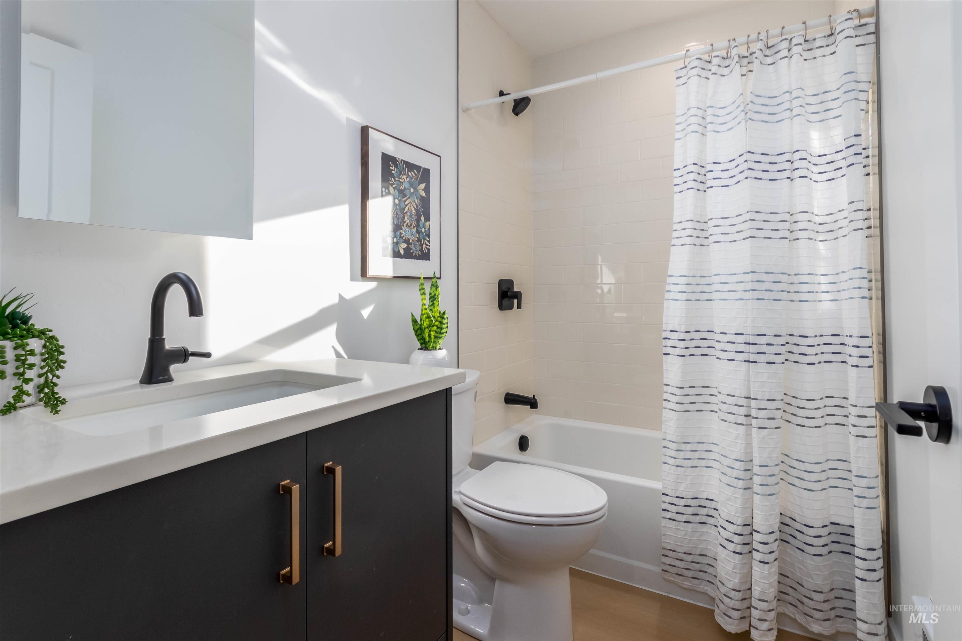 Full bathroom featuring vanity, shower / bath combo, and light wood-style flooring