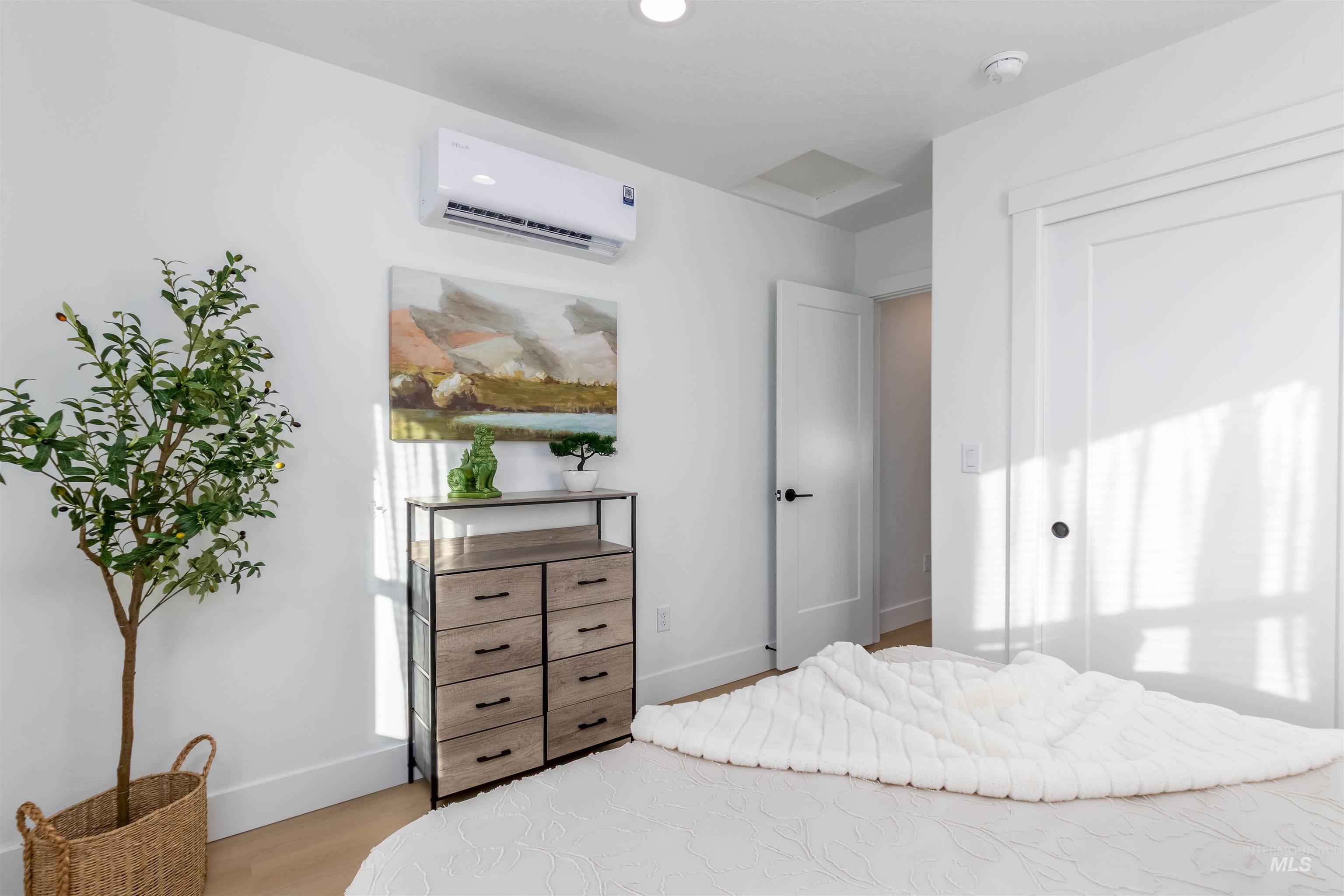 Bedroom featuring a wall mounted air conditioner, light wood-type flooring, and recessed lighting