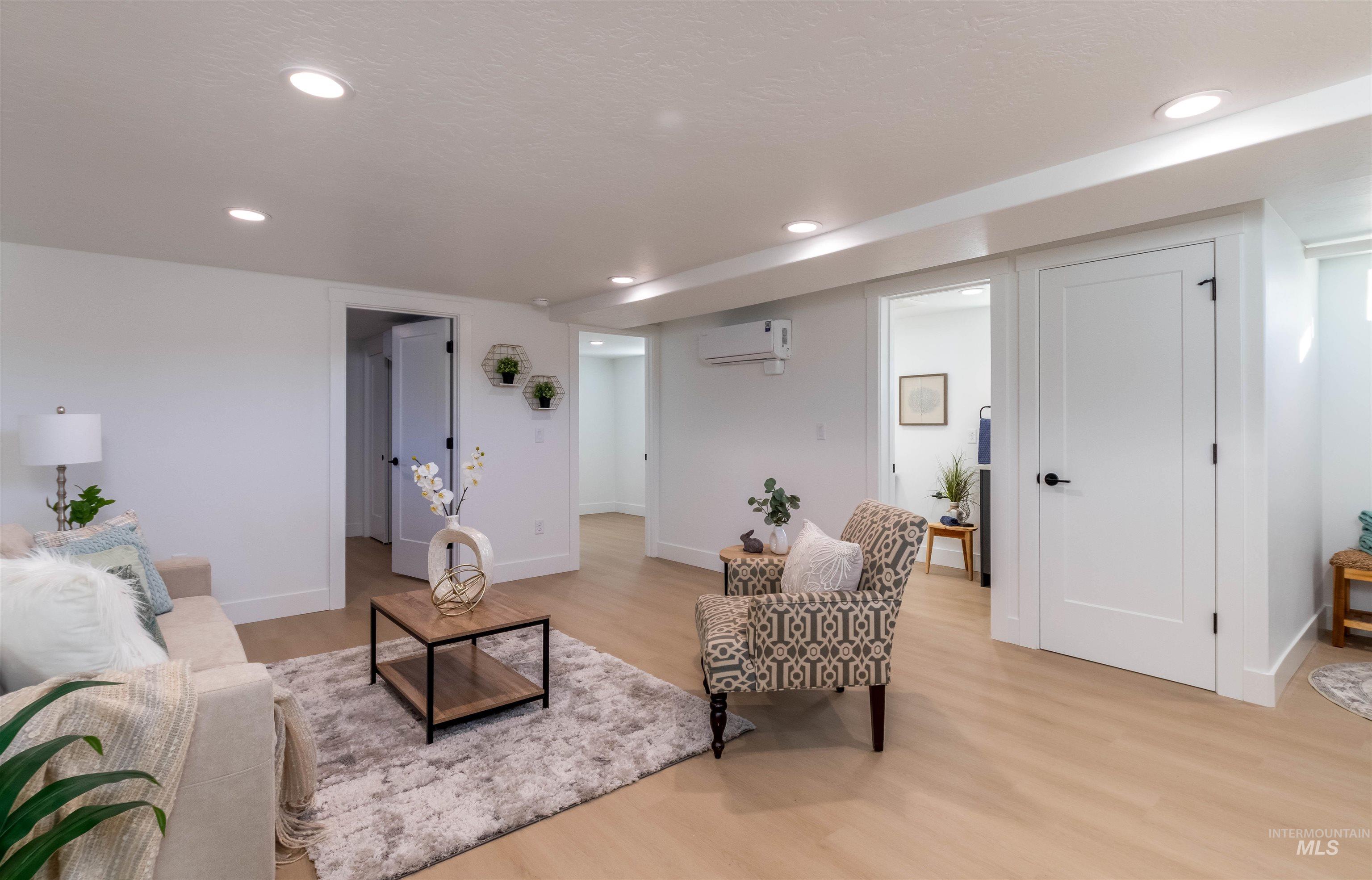 Living room with light wood-type flooring, recessed lighting, a wall mounted AC, and a textured ceiling