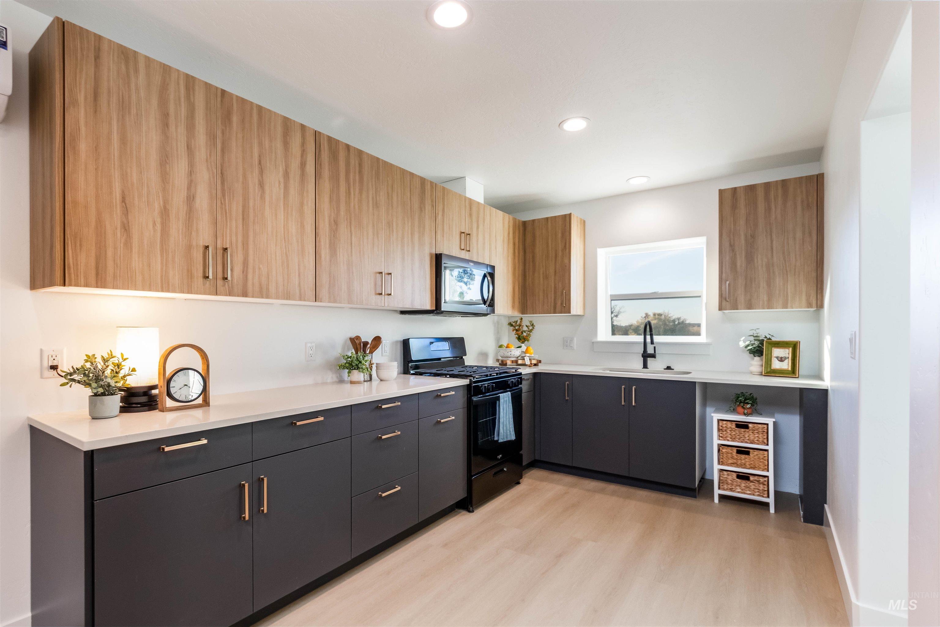 Kitchen with black appliances, modern cabinets, light wood-style flooring, and recessed lighting