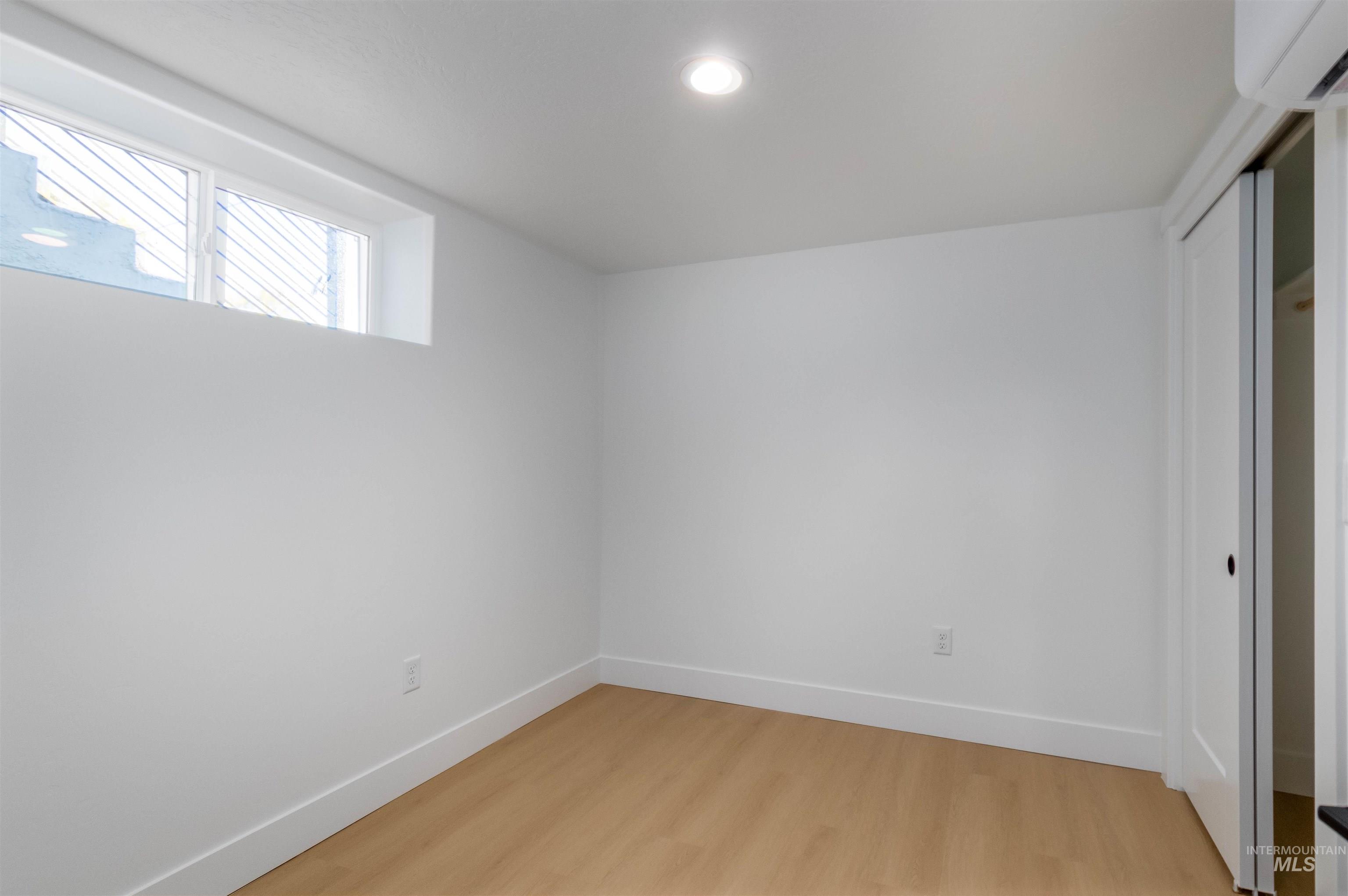 Unfurnished bedroom with a closet, light wood-style flooring, a wall mounted AC, and recessed lighting