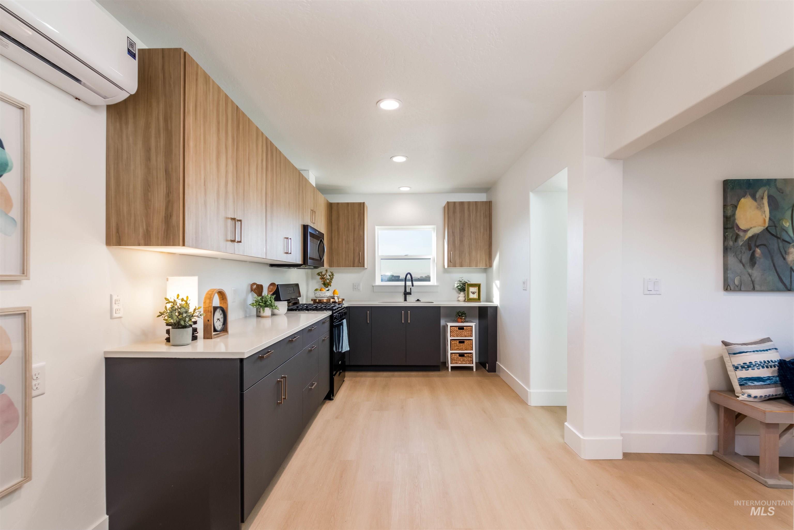 Kitchen featuring modern cabinets, a wall unit AC, black range with gas stovetop, light wood-type flooring, and recessed lighting