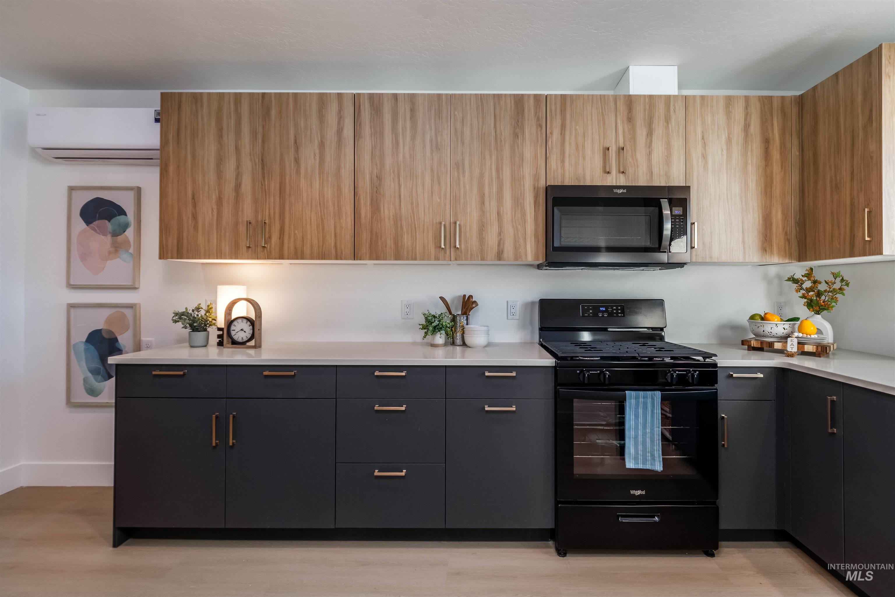 Kitchen featuring black gas range oven, modern cabinets, stainless steel microwave, and light wood-style flooring