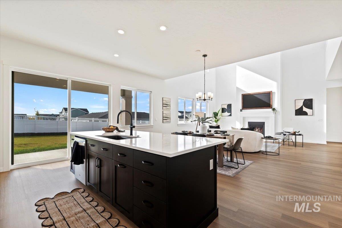 Kitchen featuring a warm lit fireplace, decorative light fixtures, dark wood-style floors, open floor plan, and recessed lighting