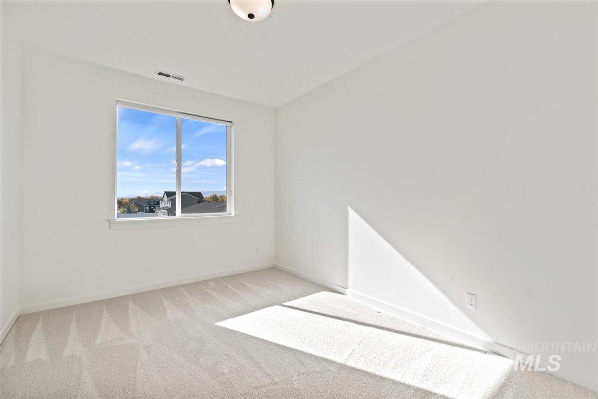 Empty room with light colored carpet and baseboards
