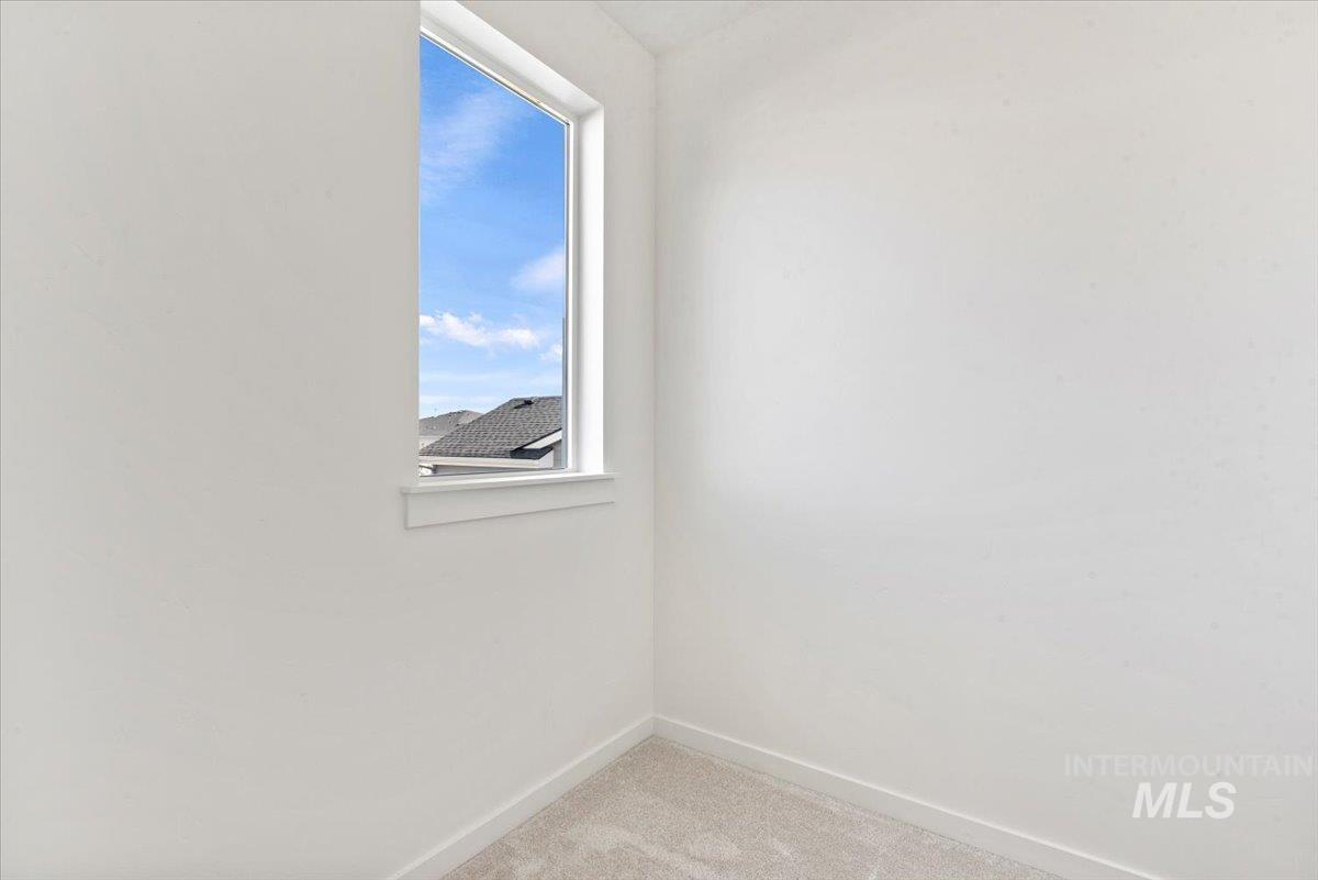 Empty room featuring light carpet and baseboards
