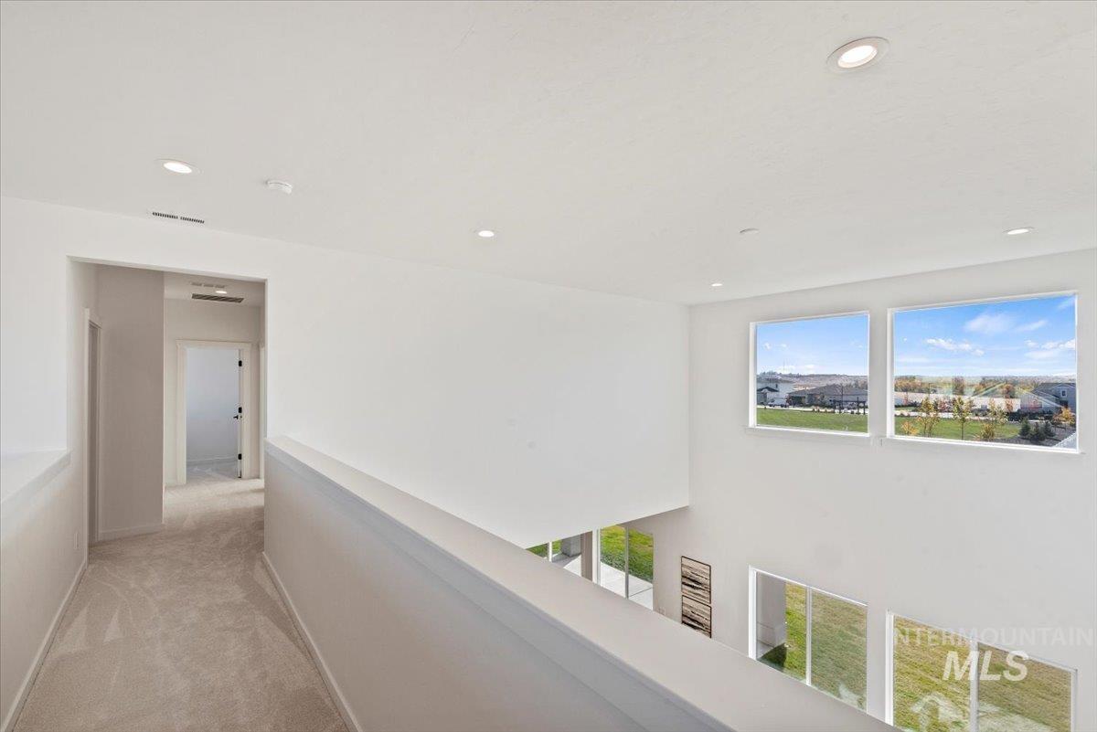 Hallway featuring plenty of natural light, recessed lighting, light colored carpet, and an upstairs landing